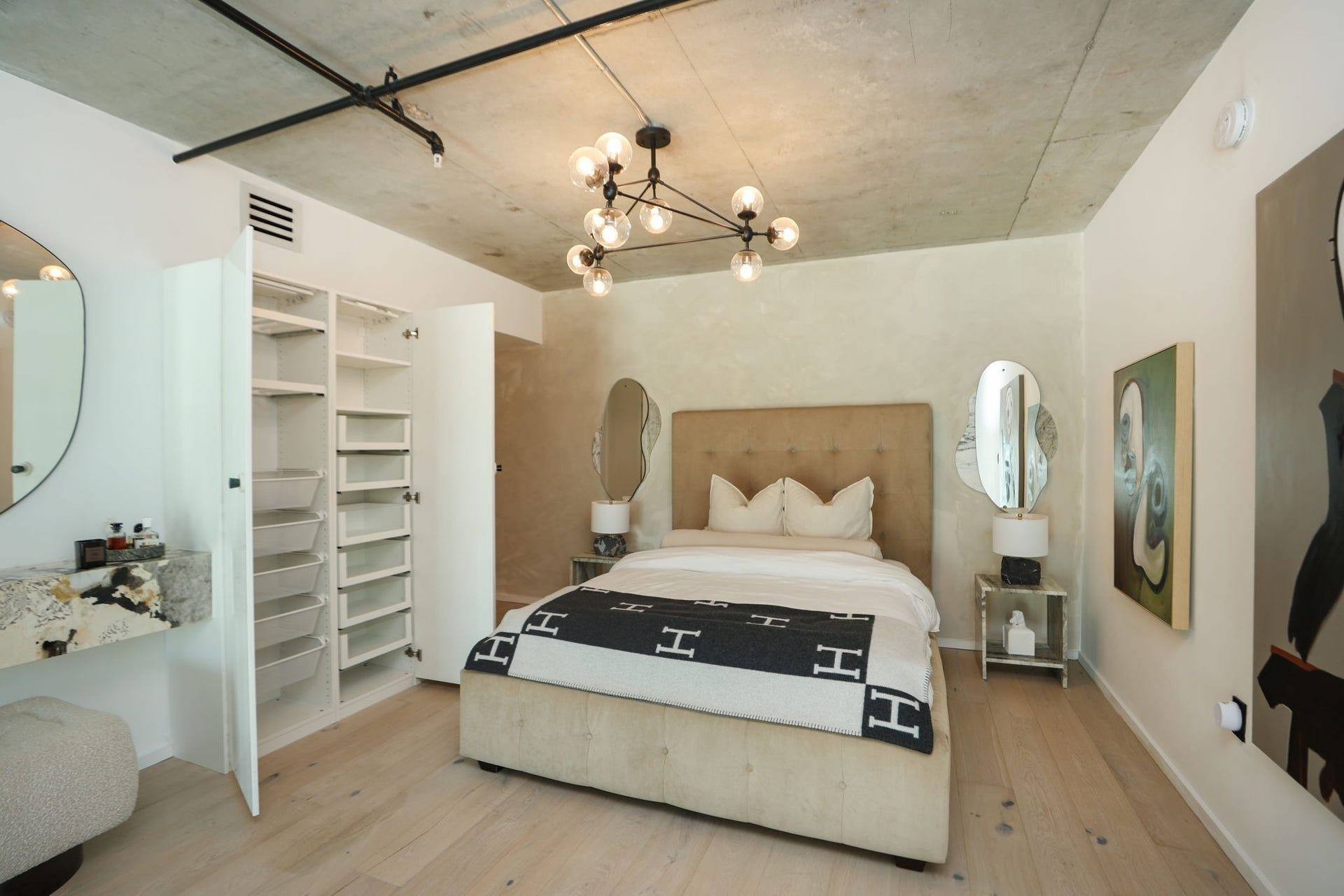 Built-in wardrobe with open shelving and pull out drawers, plus a floating marble vanity, in the primary bedroom.