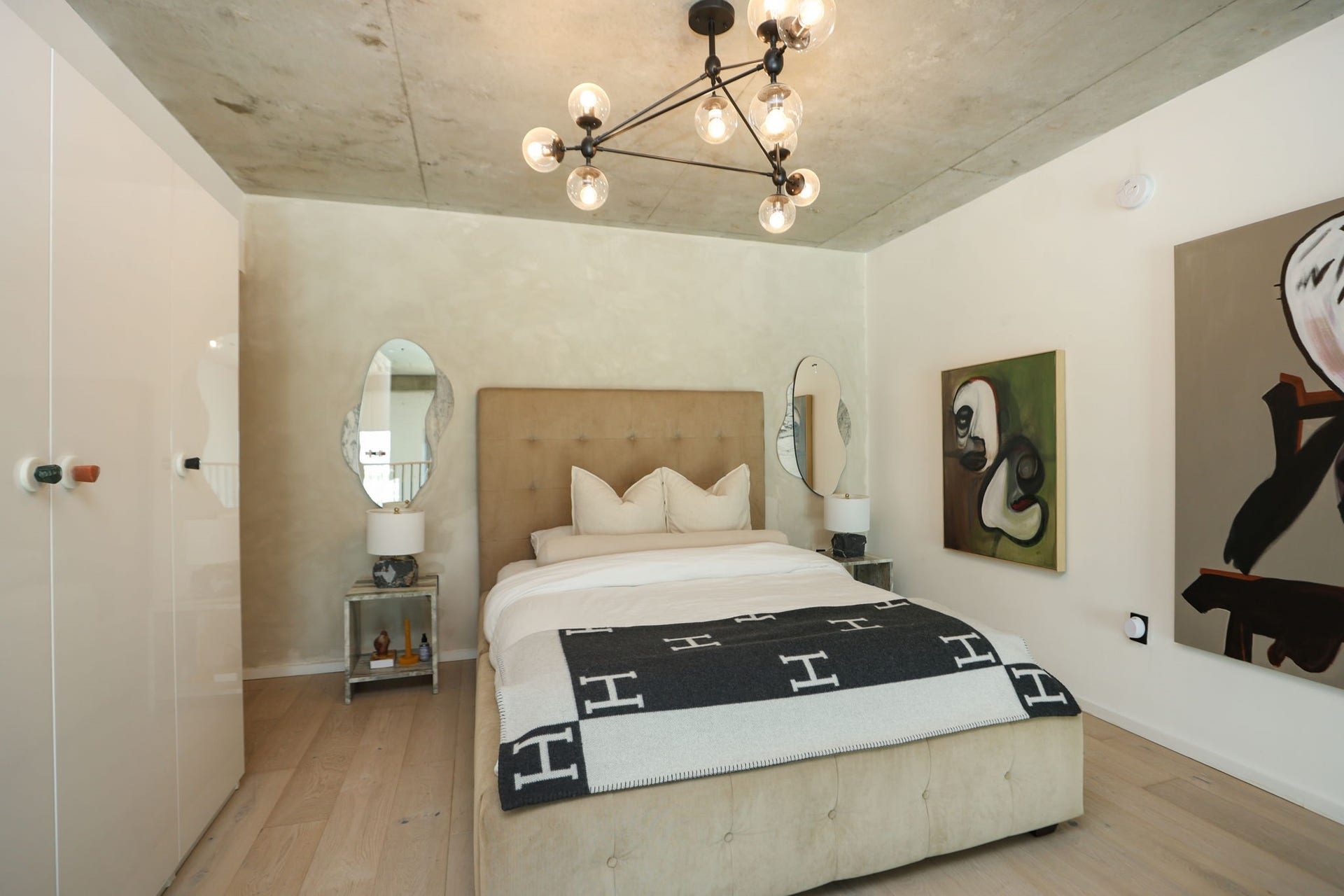 Textured limewash walls, accent mirrors, globe chandelier, and curated artwork create a serene boutique-hotel feel.