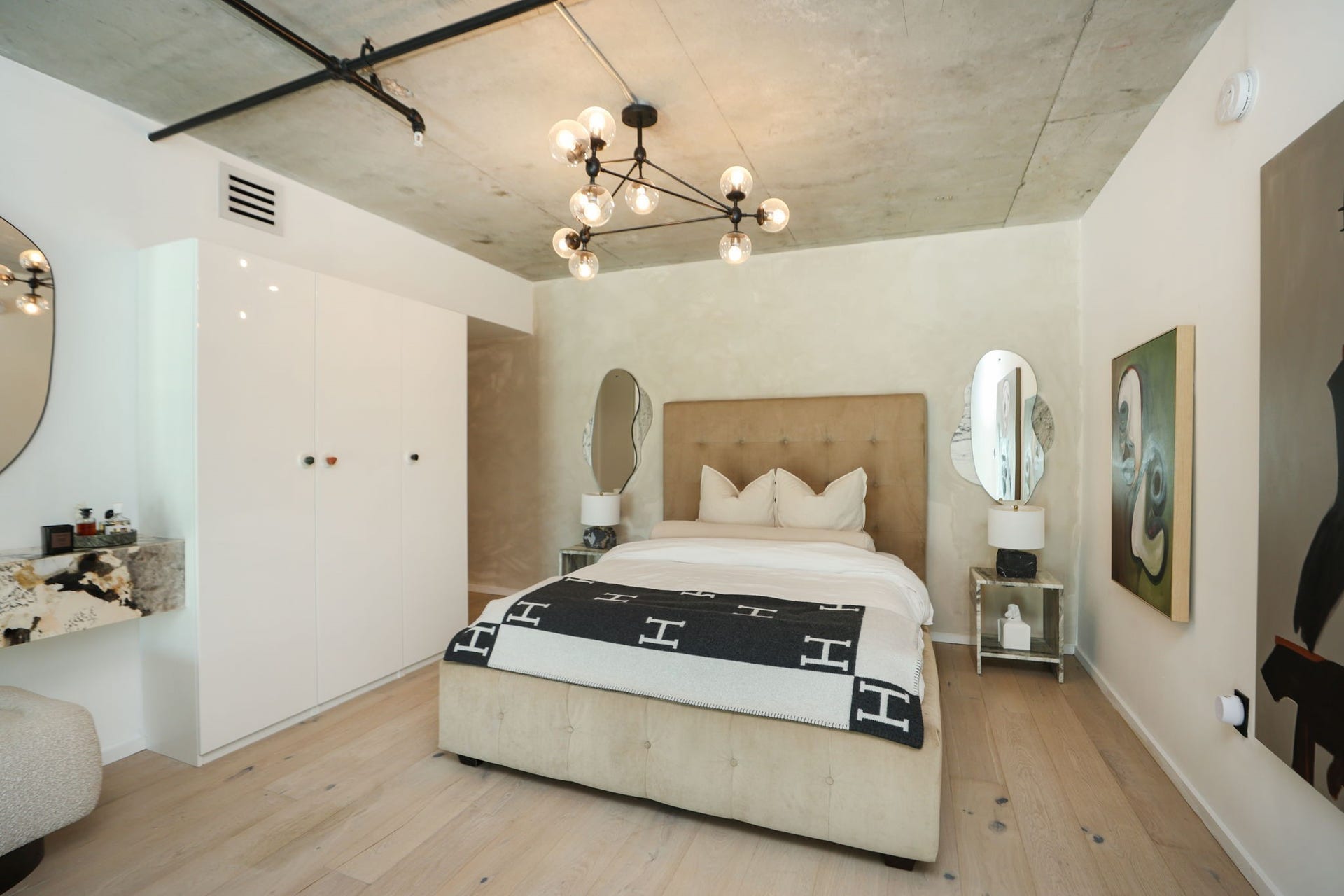 Exposed concrete ceilings and wide-plank flooring set the tone in the primary bedroom, which includes a custom closet system for all of your wardrobe needs.