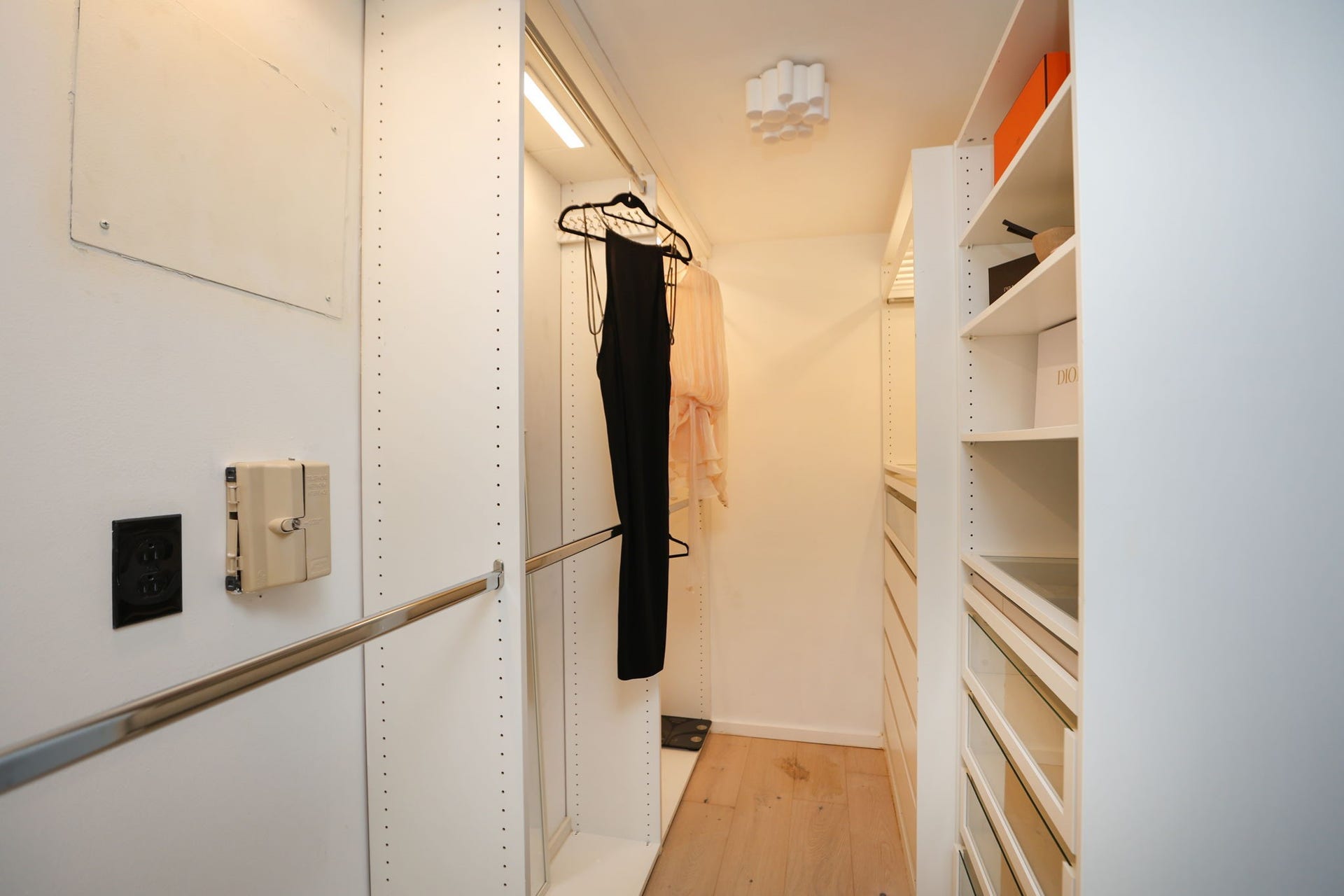 Well designed walk-in closet with oak flooring, custom shelving, generous hanging space, and drawers to organize all of your wardrobe needs.