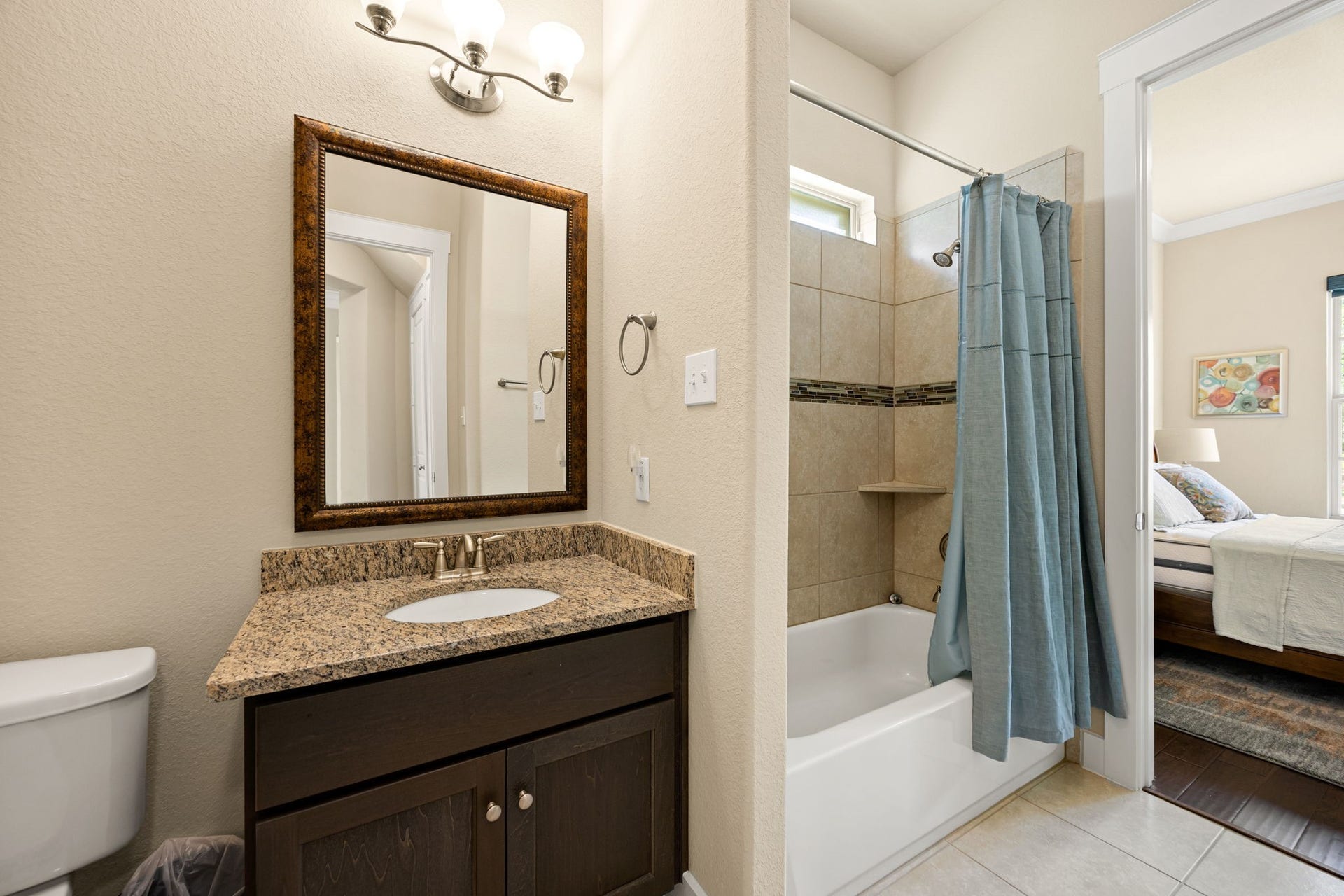 14 Kendrick Pines Boulevard, The Woodlands, TX 77389 This stylish full bath offers a refined and functional space for guests or family. A dark wood vanity with a stone countertop provides a sophisticated contrast to the neutral walls, while the tub-to-ceiling tile surround in the shower adds a touch of custom luxury. The clean design and modern fixtures ensure this space is as practical as it is beautiful.