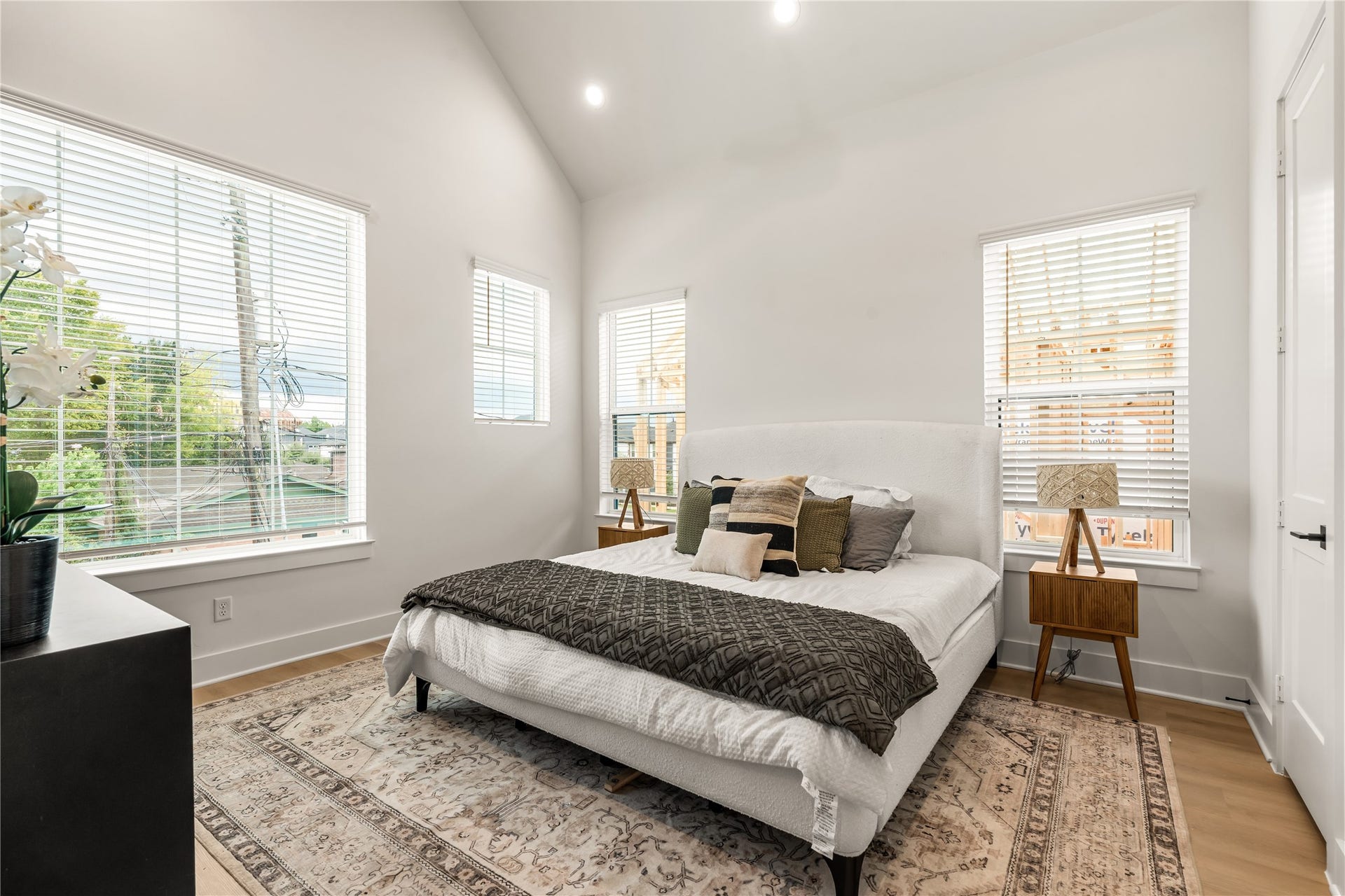Serene primary suite featuring vaulted ceilings and oversized windows for a sunlit retreat.