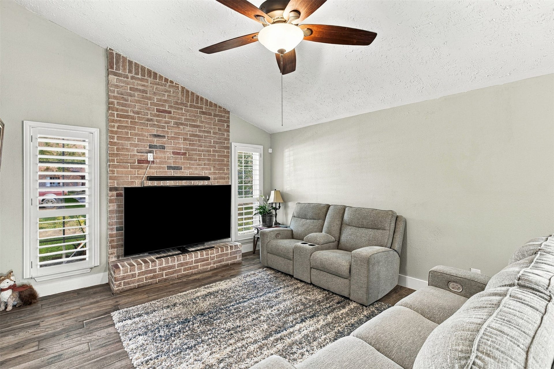 22611 Carter Moir Lane, Katy, TX 77449 Inviting living room featuring brick fireplace abundant natural light, and plantation shutters.