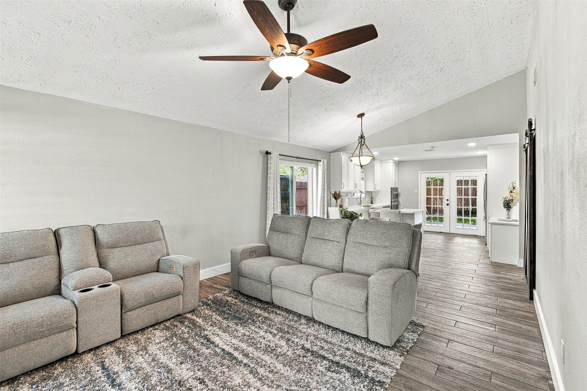 22611 Carter Moir Lane, Katy, TX 77449 Spacious living area with vaulted ceiling, updated flooring, ceiling fan, and an open flow into the dining and kitchen areas.