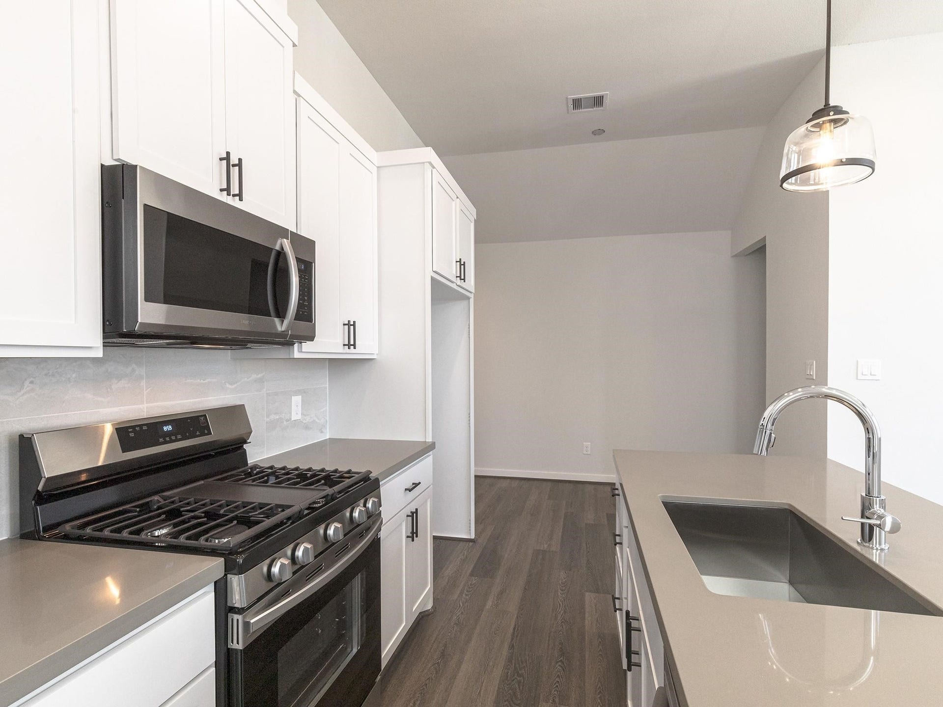 751 N Emile Street, Houston, TX 77020 Modern kitchen featuring sleek stainless steel appliances, elegant white cabinetry, and a spacious island with a stylish pendant light.
Note: Photos 2022