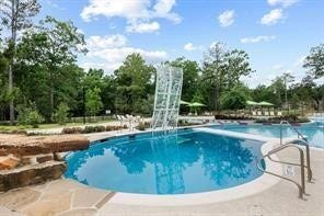 230 Elianne Lace Court, Conroe, TX 77318 A dedicated dive pool with a rock climbing wall provides a safe and exciting water play space for children, conveniently located adjacent to the main pool and shaded seating.