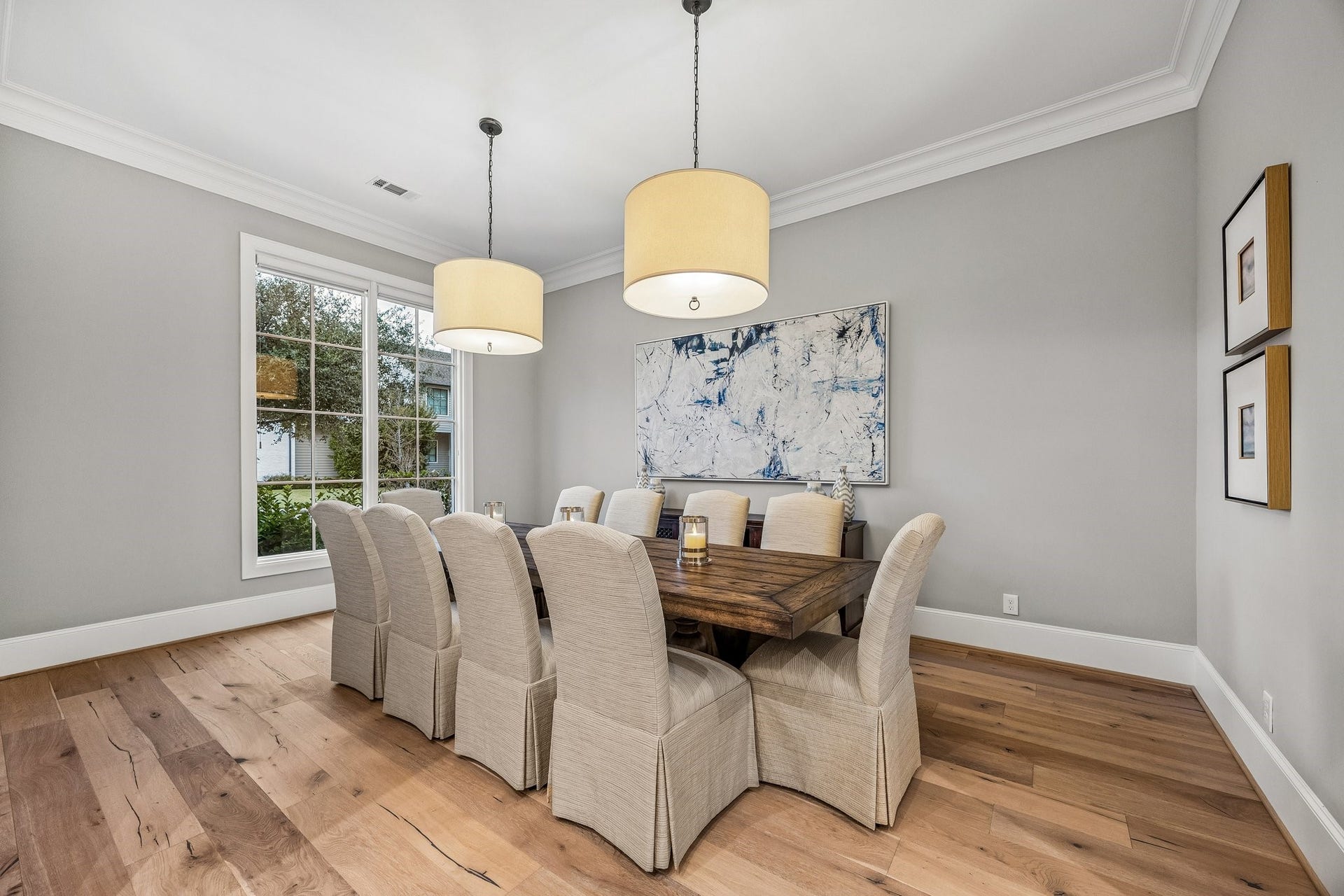 The generously sized dining room features two contemporary drum pendant chandeliers, wide plank floors, crown molding and 8 Inch baseboards.