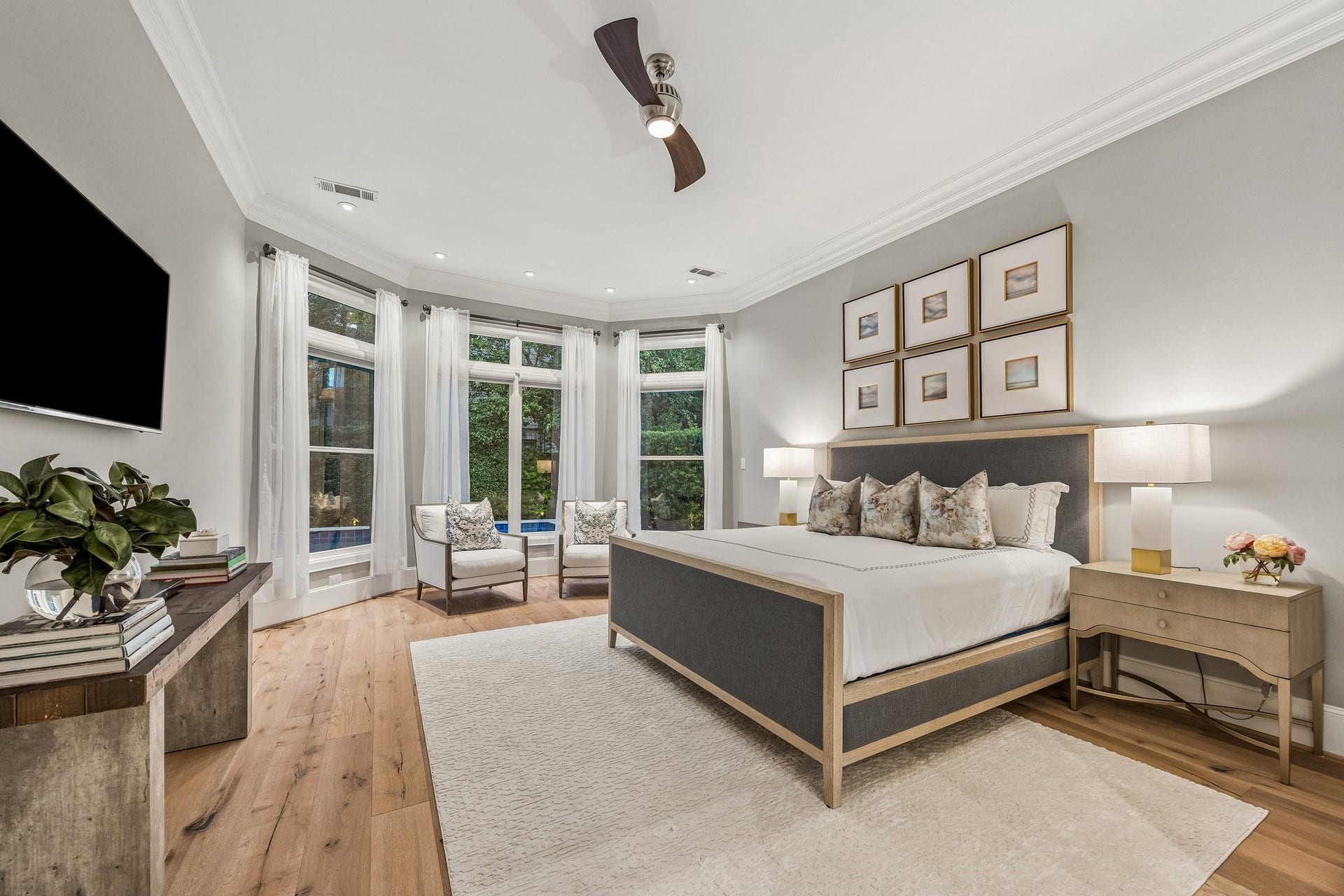 Generously proportioned Primary Suite with a stunning curved wall of expansive windows.  LED recessed lighting, wide plank floors, crown molding, 8 Inch baseboards, Linear ceiling fan, and window treatments.