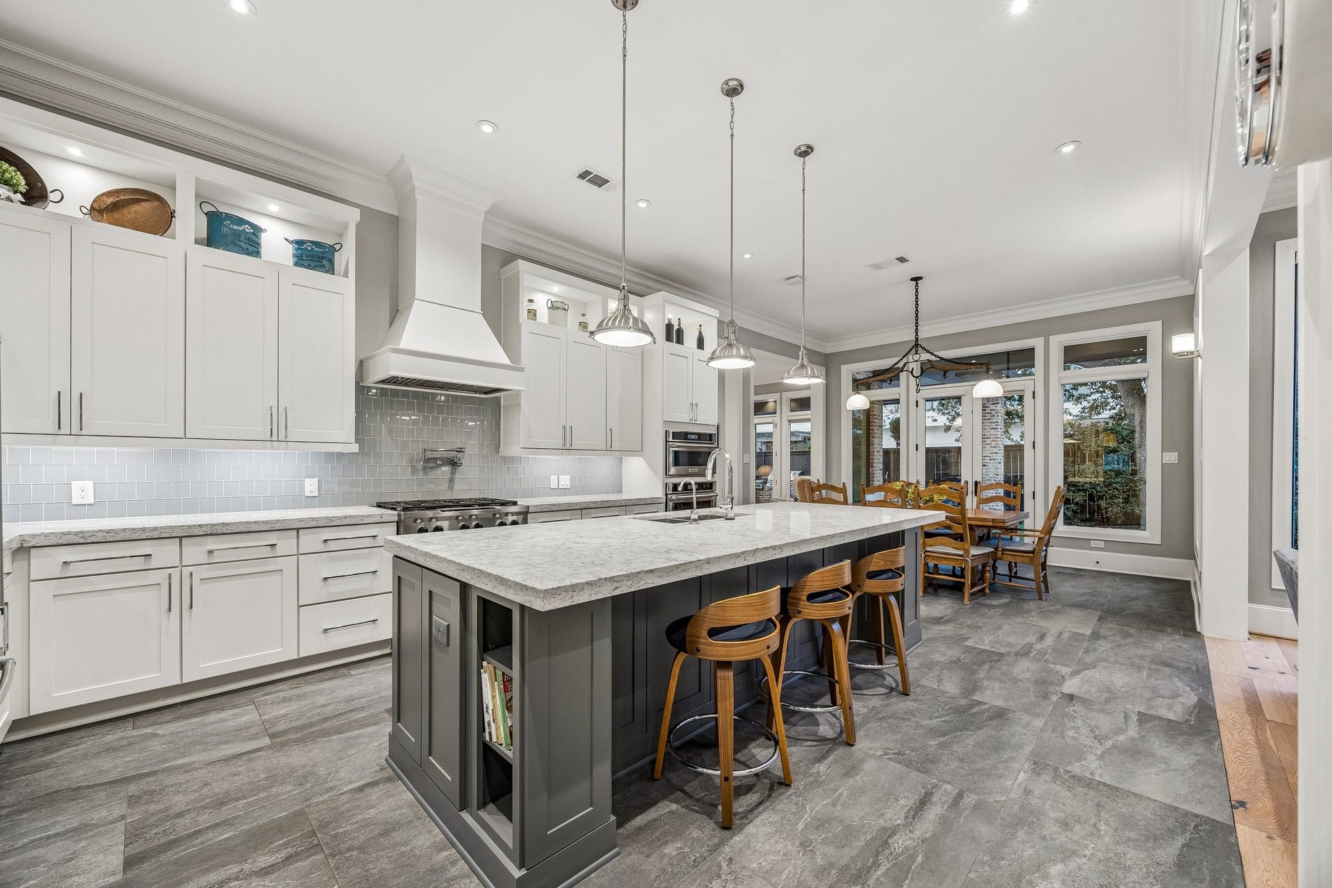 Rich charcoal-toned tile flooring provides a beautiful contrast to the Classic Carrara Stone Counters and the grey/blue toned subway tile backsplash.