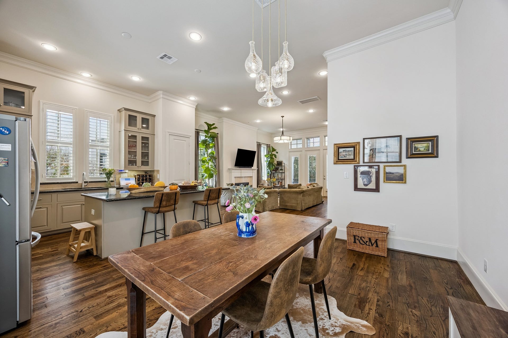 2721 Cohn Street, Houston, TX 77007 Dining area flows seamlessly between the kitchen & living room, featuring wood floors, crown molding & a distinctive pendant light fixture that defines the space while maintaining the open layout.