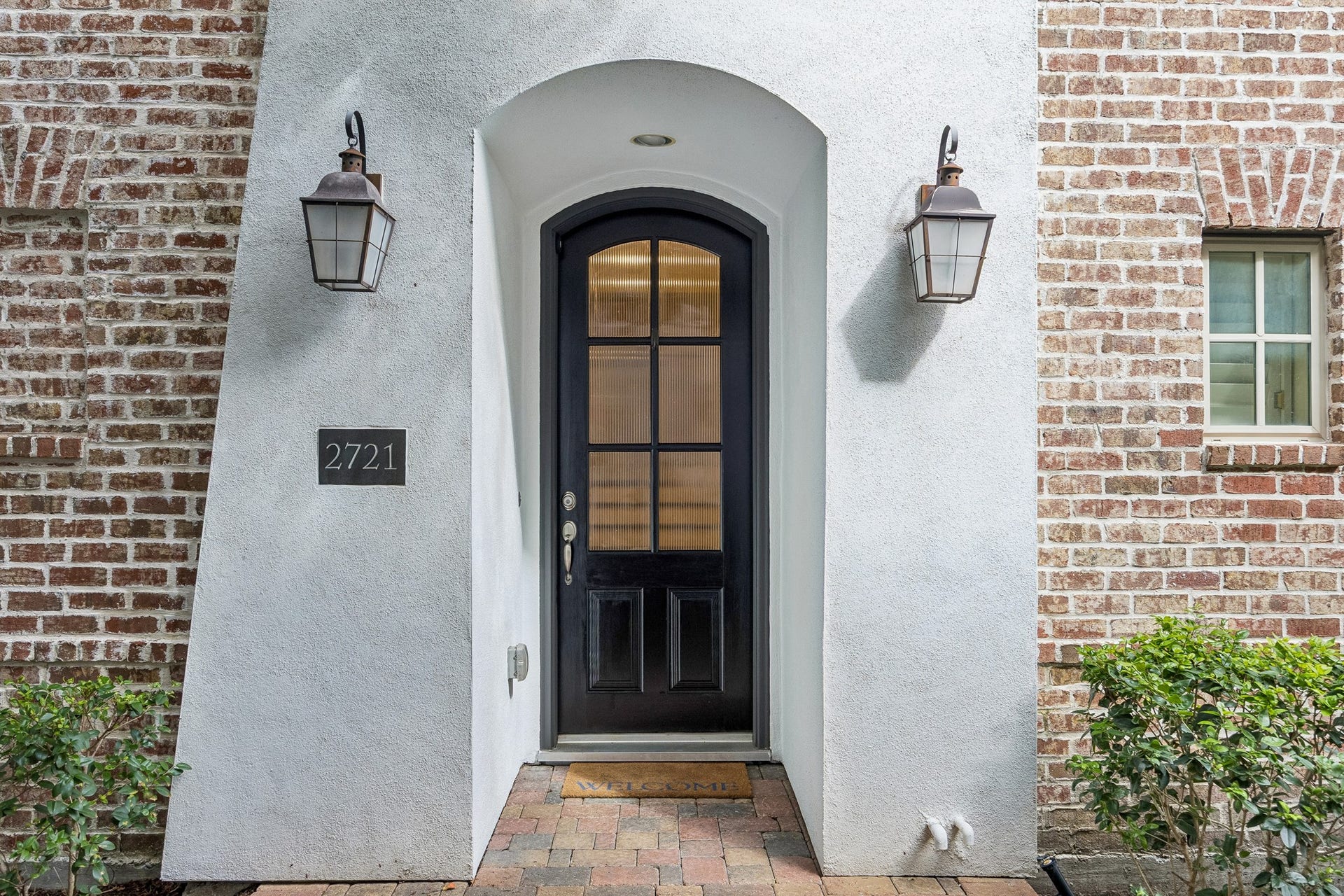 2721 Cohn Street, Houston, TX 77007 Inviting arched entry features a distinctive glass-paneled front door framed by brick accents & classic exterior lanterns, creating a welcoming first impression at 2721 Cohn St.