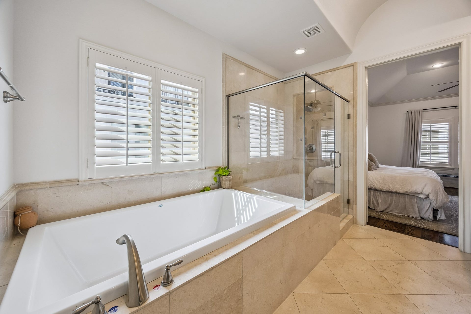 2721 Cohn Street, Houston, TX 77007 Large soaking tub sits beneath plantation-shuttered windows, complemented by the adjacent glass-enclosed shower & direct access to the primary suite.