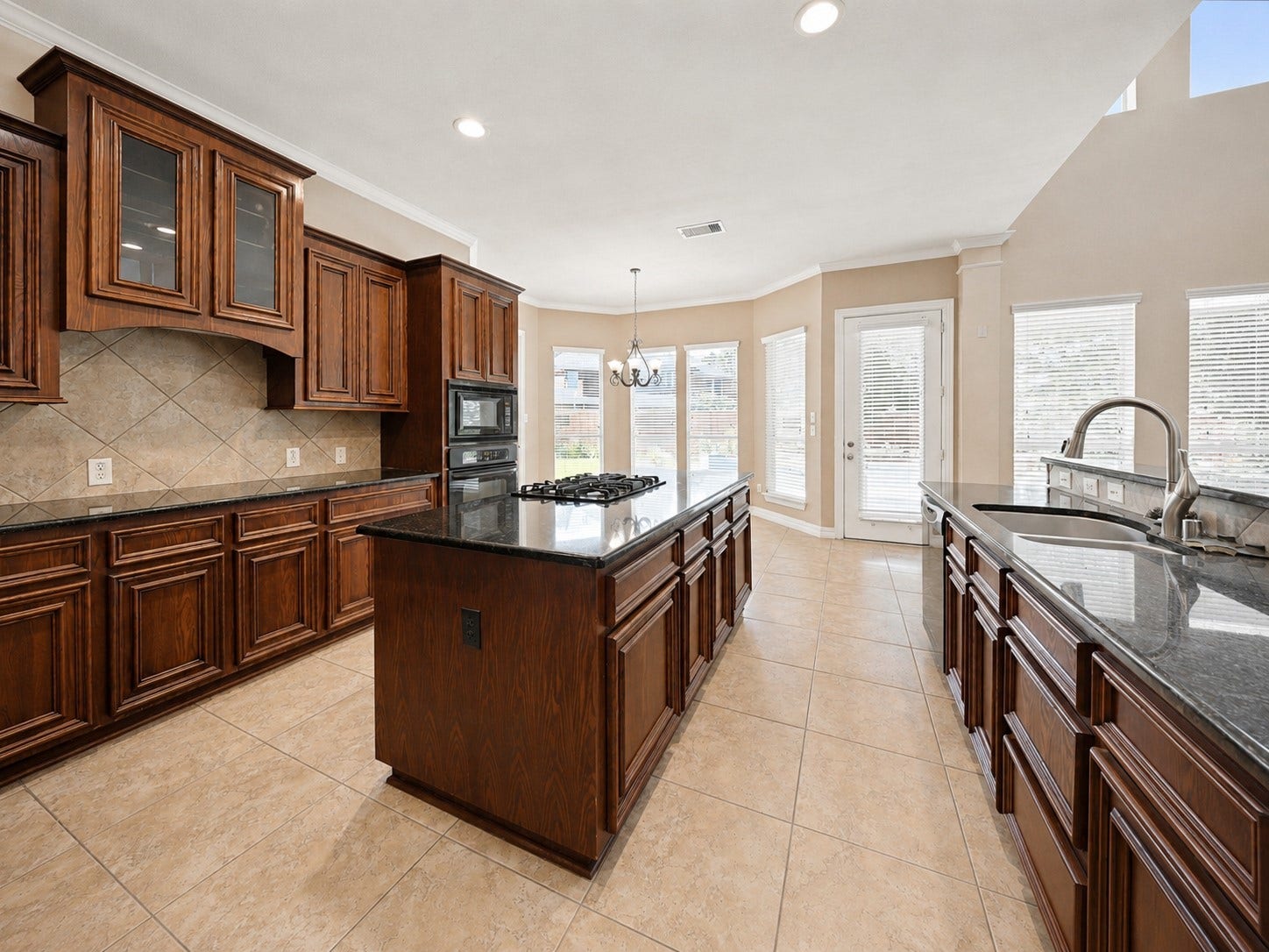 26306 Eden Point Court, Katy, TX 77494 Kitchen view toward the breakfast area featuring generous counter space, center island, tile flooring, and multiple windows providing natural light.
