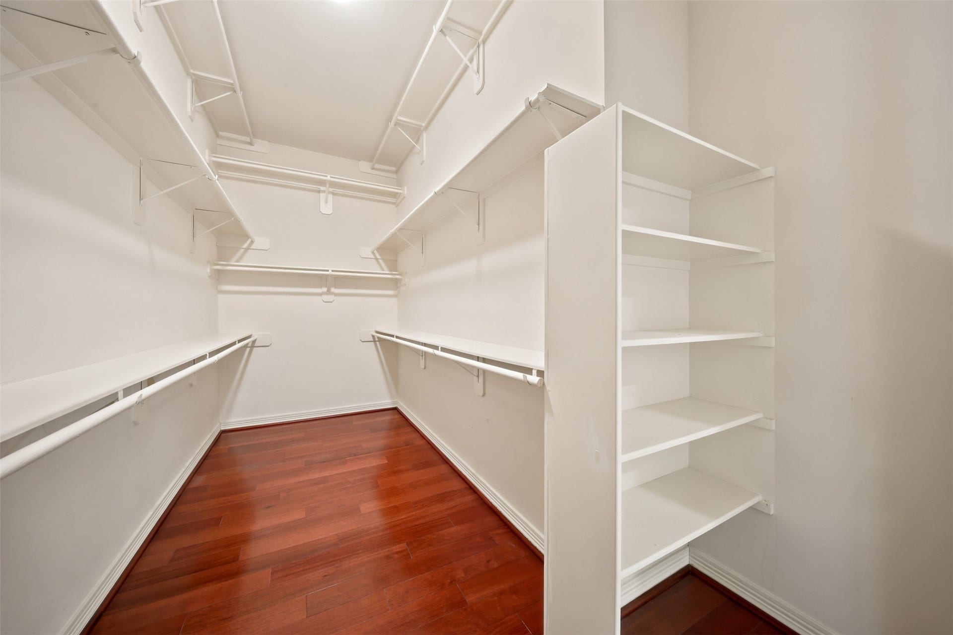 26306 Eden Point Court, Katy, TX 77494 Primary walk-in closet with hardwood flooring, extensive hanging space, built-in shelving, and organized storage.