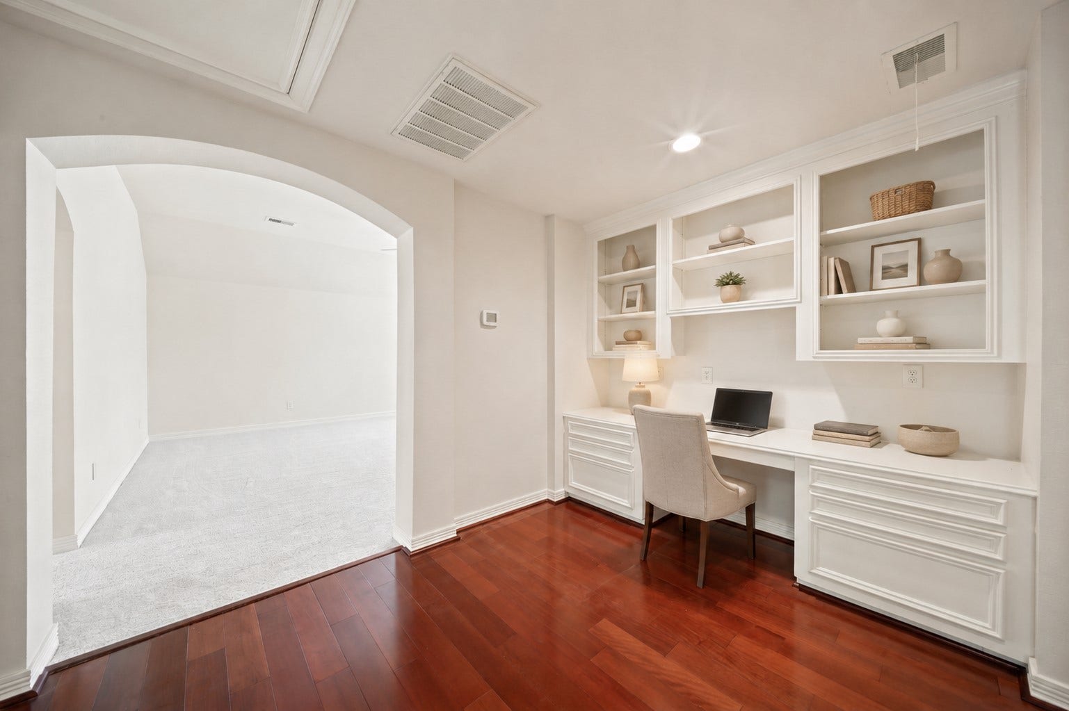 26306 Eden Point Court, Katy, TX 77494 Upstairs landing with hardwood flooring, a built-in desk, open shelving, cabinet storage, and an arched opening to the adjoining room.