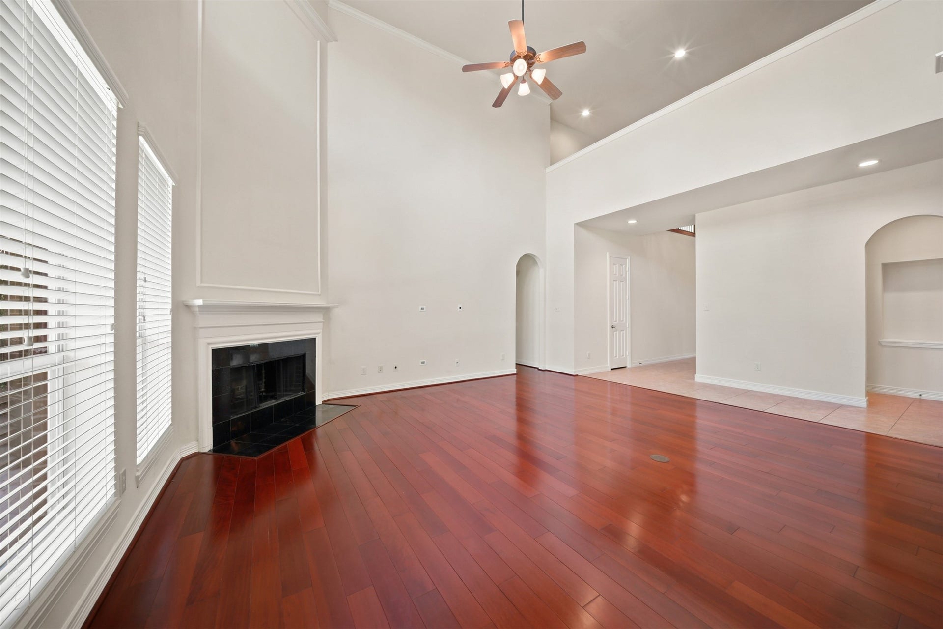 26306 Eden Point Court, Katy, TX 77494 Alternate family room view featuring the fireplace, soaring ceiling, upper-level overlook, and expansive hardwood flooring.