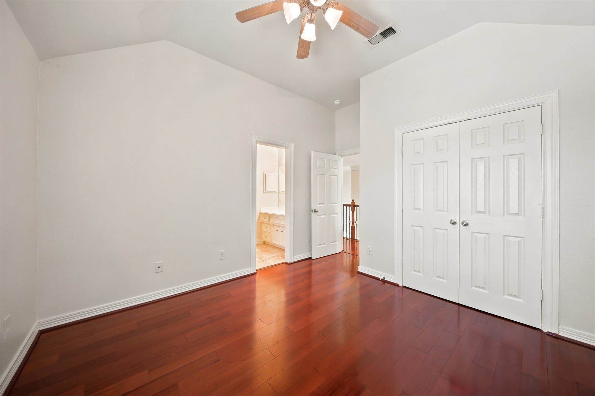 26306 Eden Point Court, Katy, TX 77494 Alternate bedroom view highlighting the vaulted ceiling, double-door closet, hardwood flooring, and access to a private vanity area.
