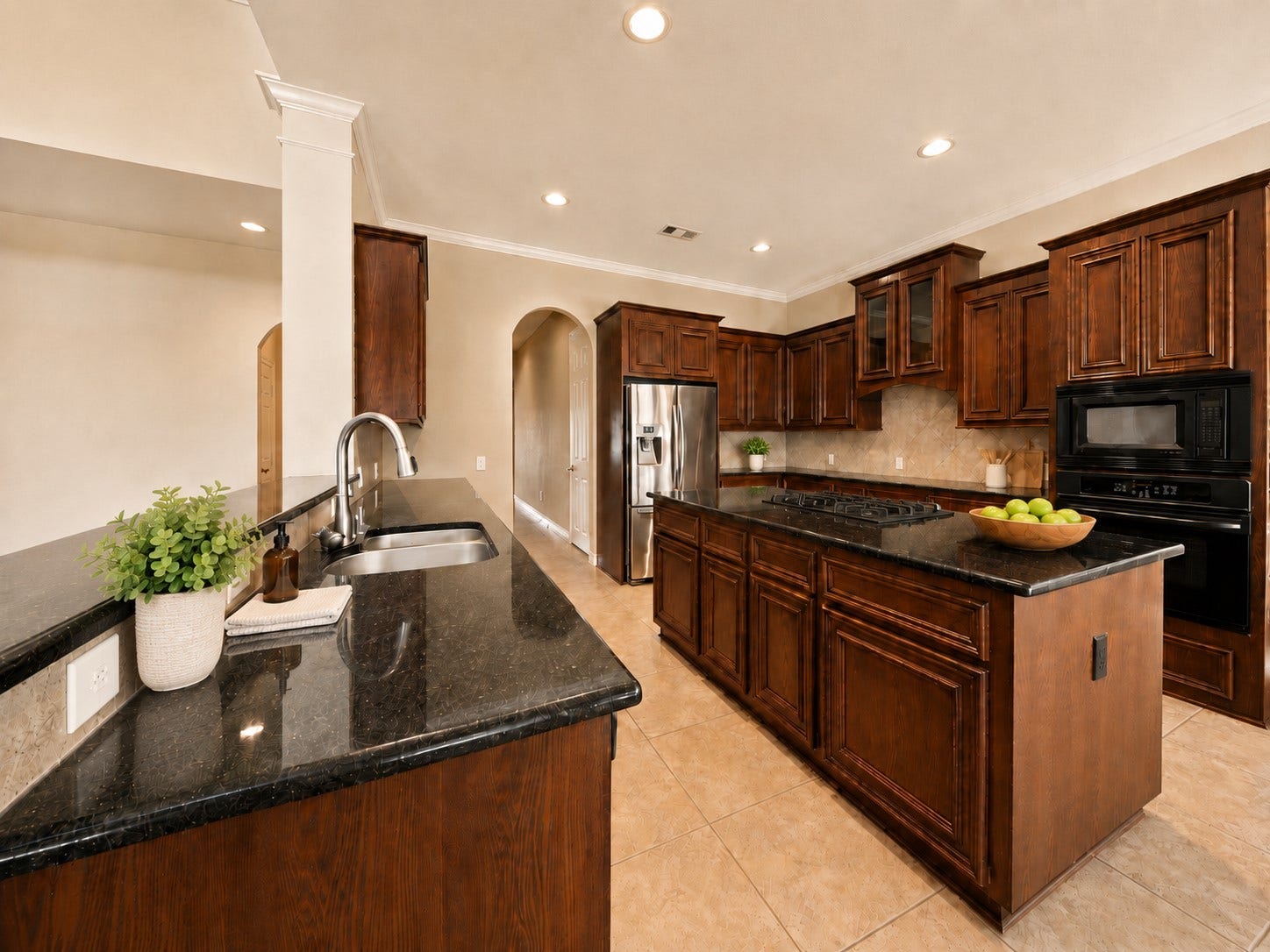 26306 Eden Point Court, Katy, TX 77494 Angled kitchen view highlighting the granite-topped island, abundant cabinetry, double sink, tiled backsplash, and built-in appliances.