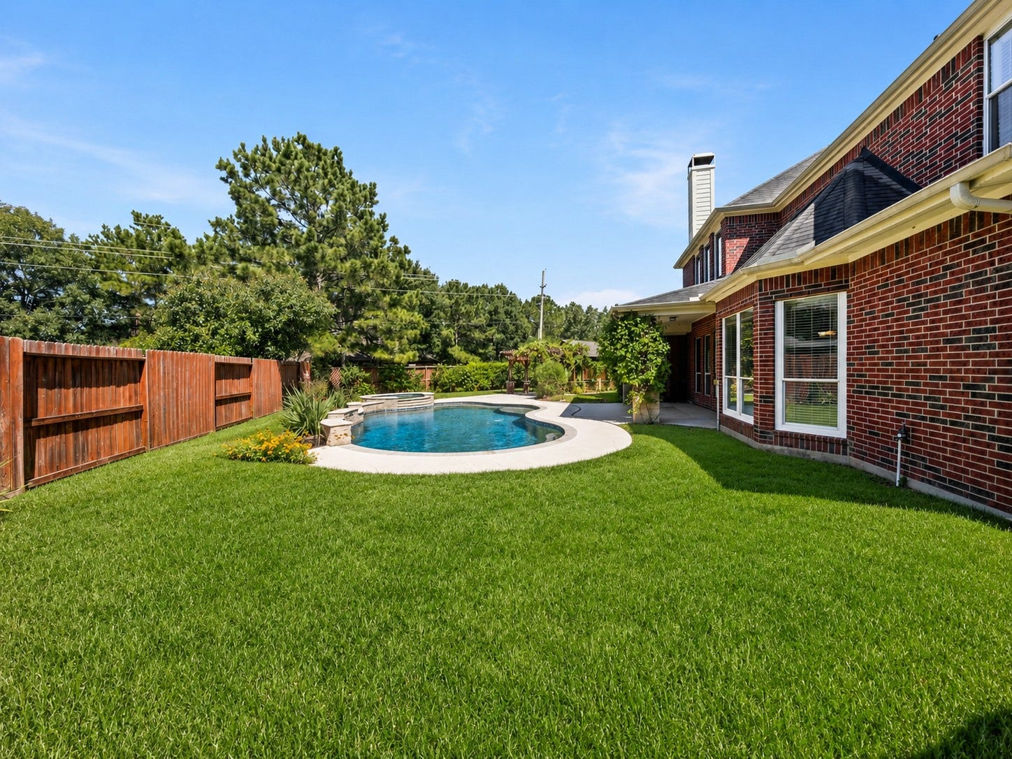 26306 Eden Point Court, Katy, TX 77494 Wide backyard view highlighting the pool, lawn, landscaping, and brick rear elevation.