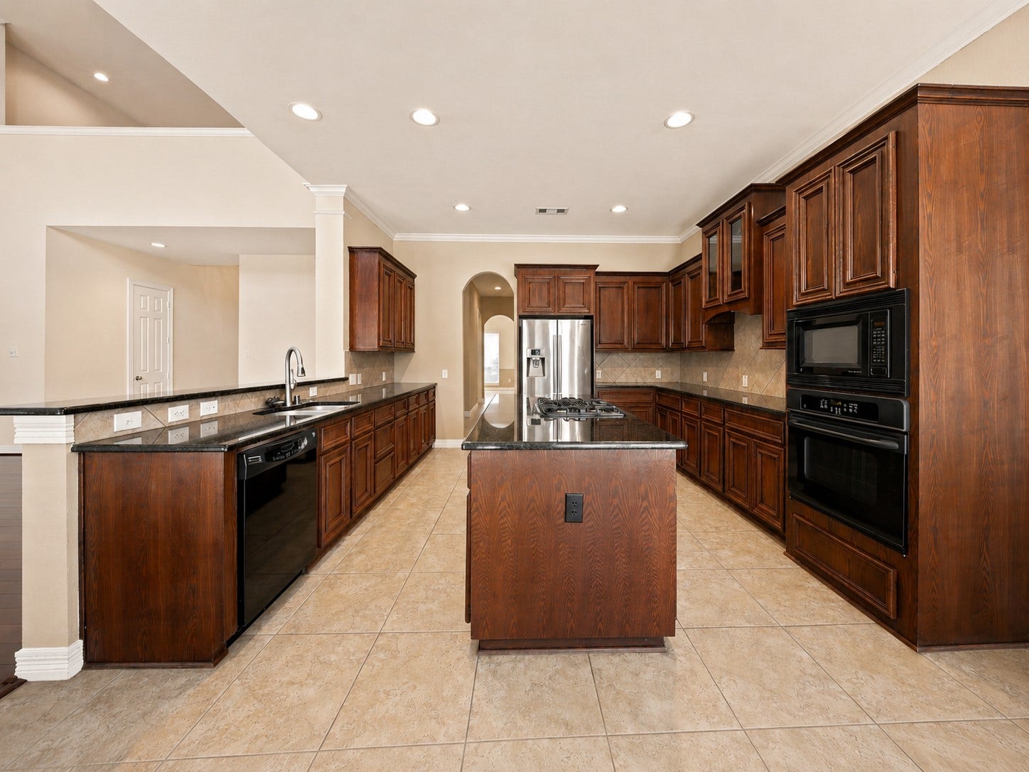 26306 Eden Point Court, Katy, TX 77494 Spacious kitchen with rich wood cabinetry, granite countertops, a large center island with gas cooktop, and extensive recessed lighting.