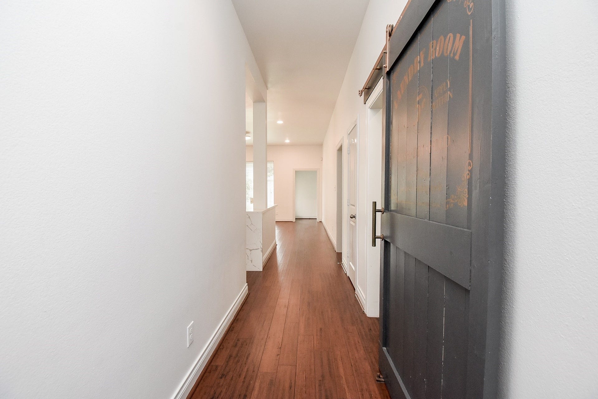 A beautiful sliding barn door serves as a unique architectural feature, concealing the laundry room while adding warmth and character to the hallway.