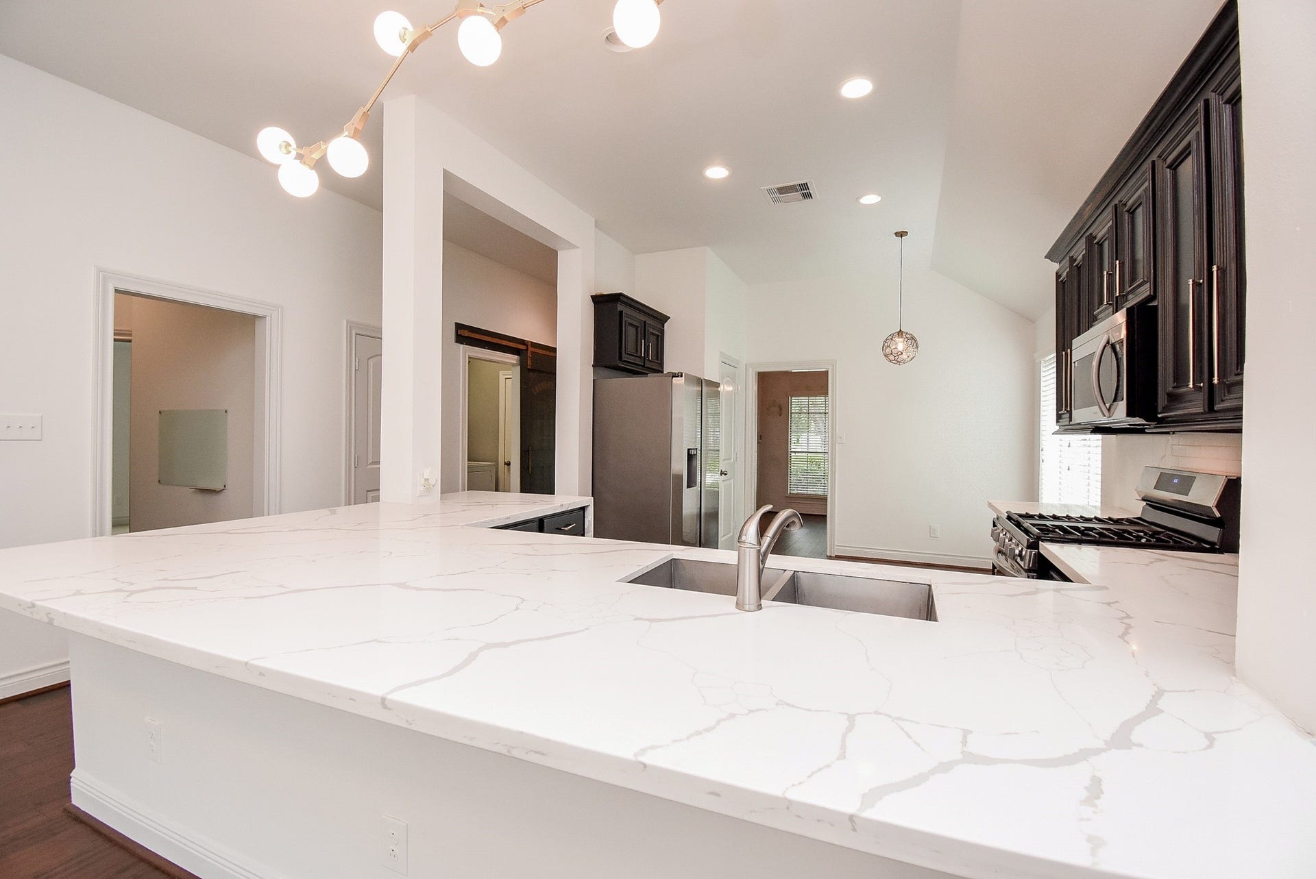 The expansive quartz island is the centerpiece of this beautifully designed kitchen, combining generous workspace, a built-in sink, and an inviting setting for gathering with family and friends. The open-concept layout enhances both functionality and everyday comfort.