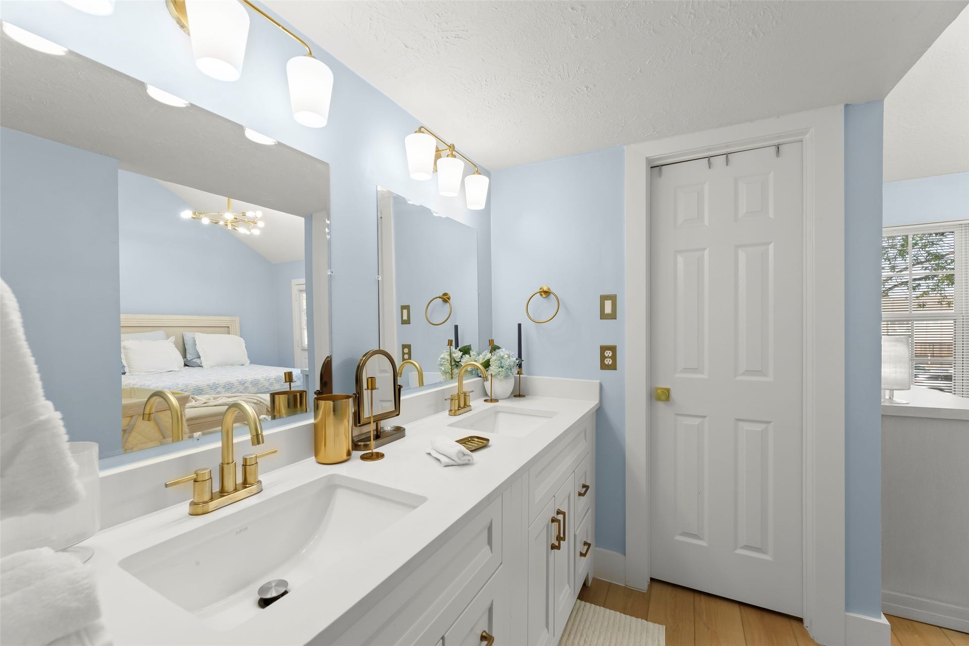 Sleek and modern bathroom featuring a double vanity with elegant gold fixtures, complemented by soft lighting and a spacious walk-in shower for a touch of luxury.