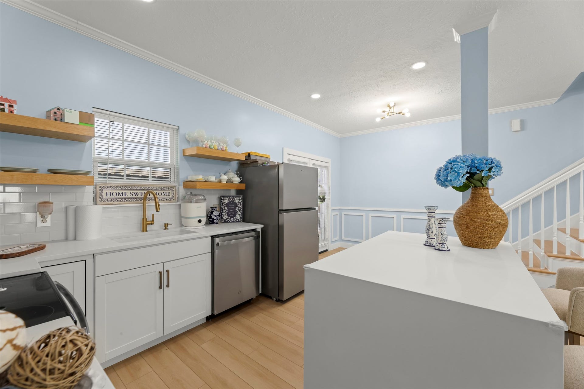 Bright and inviting open-concept living area featuring a modern kitchen with a central island, cozy seating, and light wood flooring.