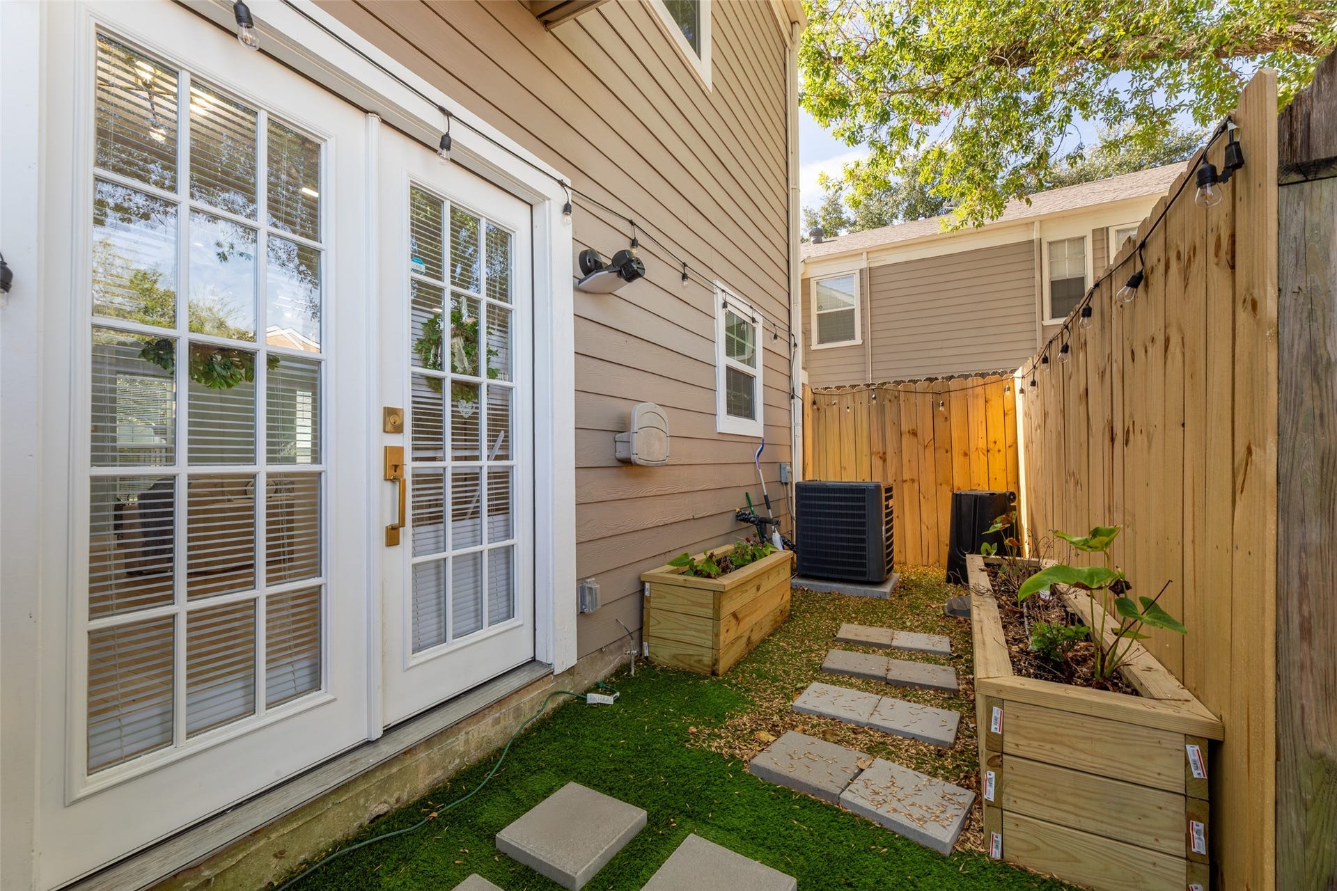 Charming townhouse with a welcoming teal door, brick facade, and cozy balcony. Surrounded by well-maintained landscaping and a neat pathway leading to the entrance.