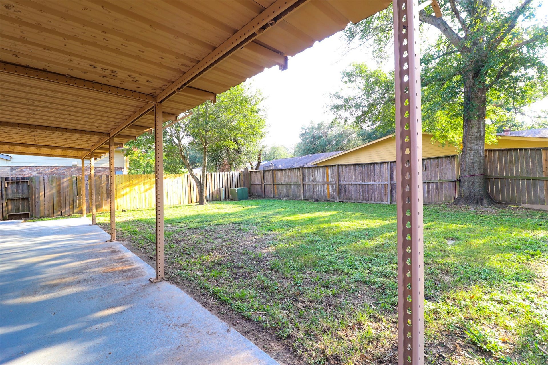Another view of covered back patio overlooking fenced backyard.
