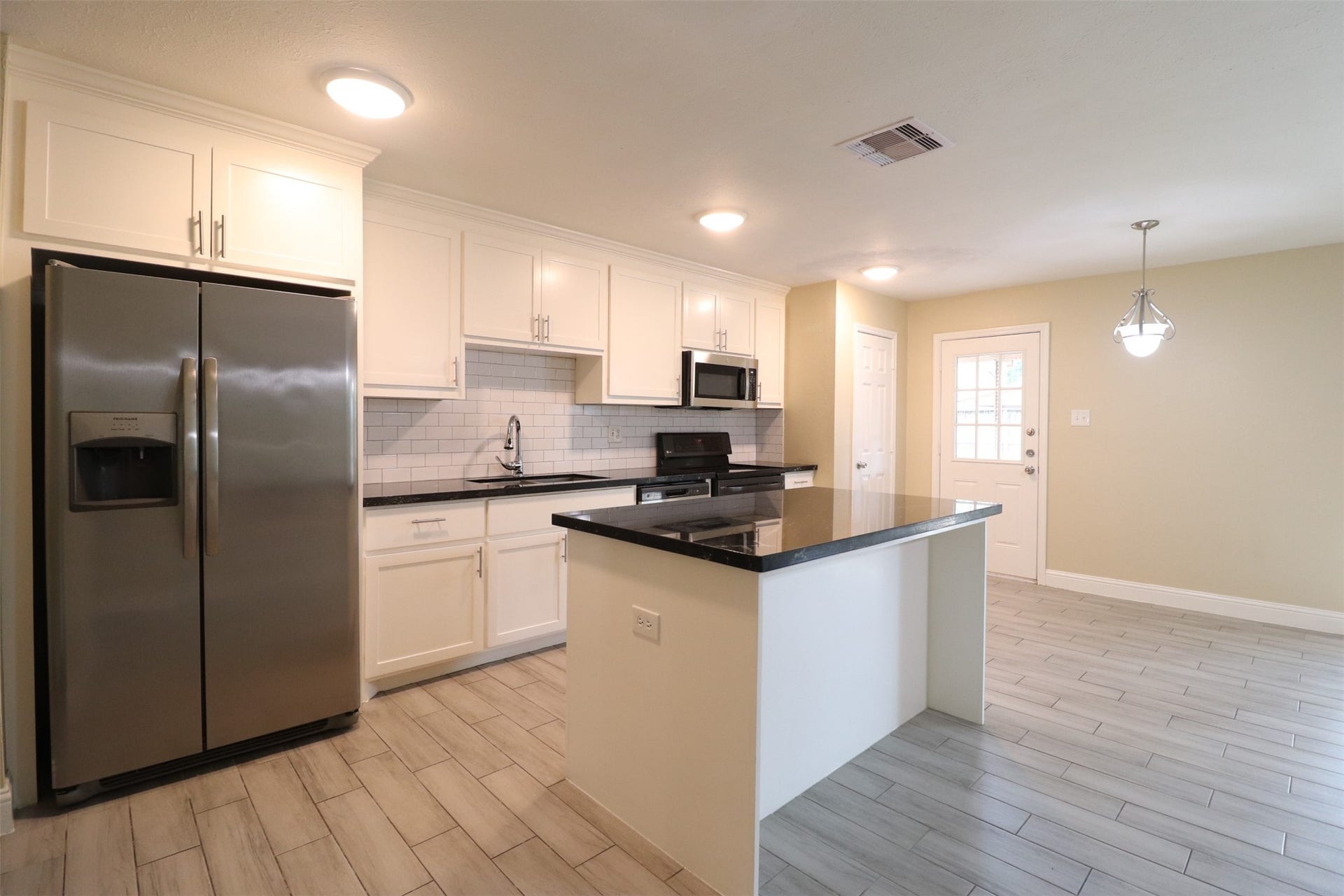 Kitchen with island, electric range, microwave, dishwasher, and refrigerator.