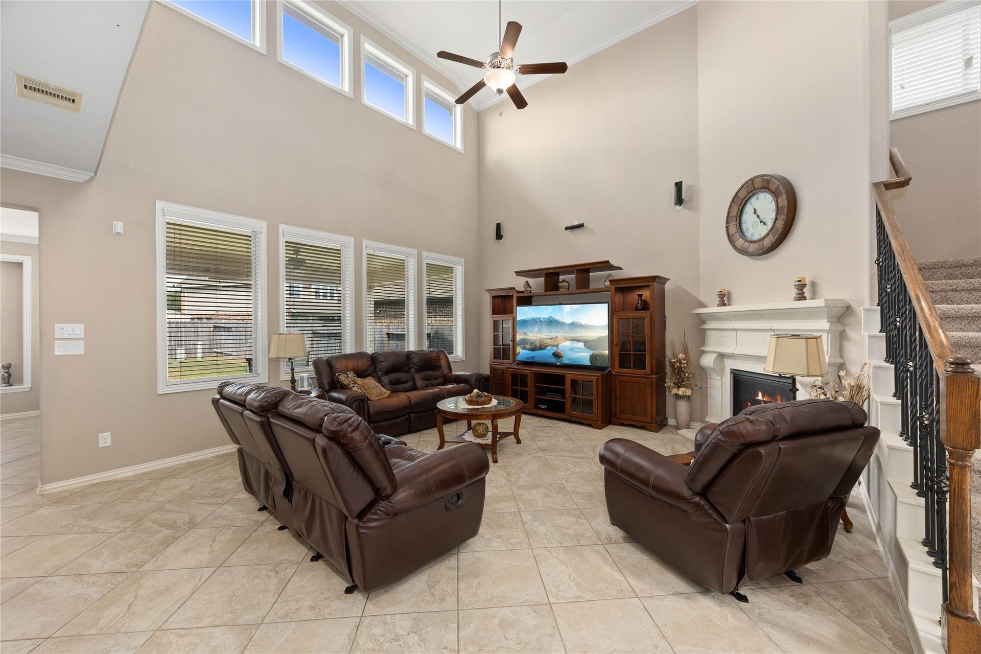 18707 Fox Kestrel Trail, Cypress, TX 77429 Spacious living room featuring high ceilings, abundant natural light from multiple windows, elegant tile flooring, and a cozy fireplace, perfect for relaxation and entertainment.