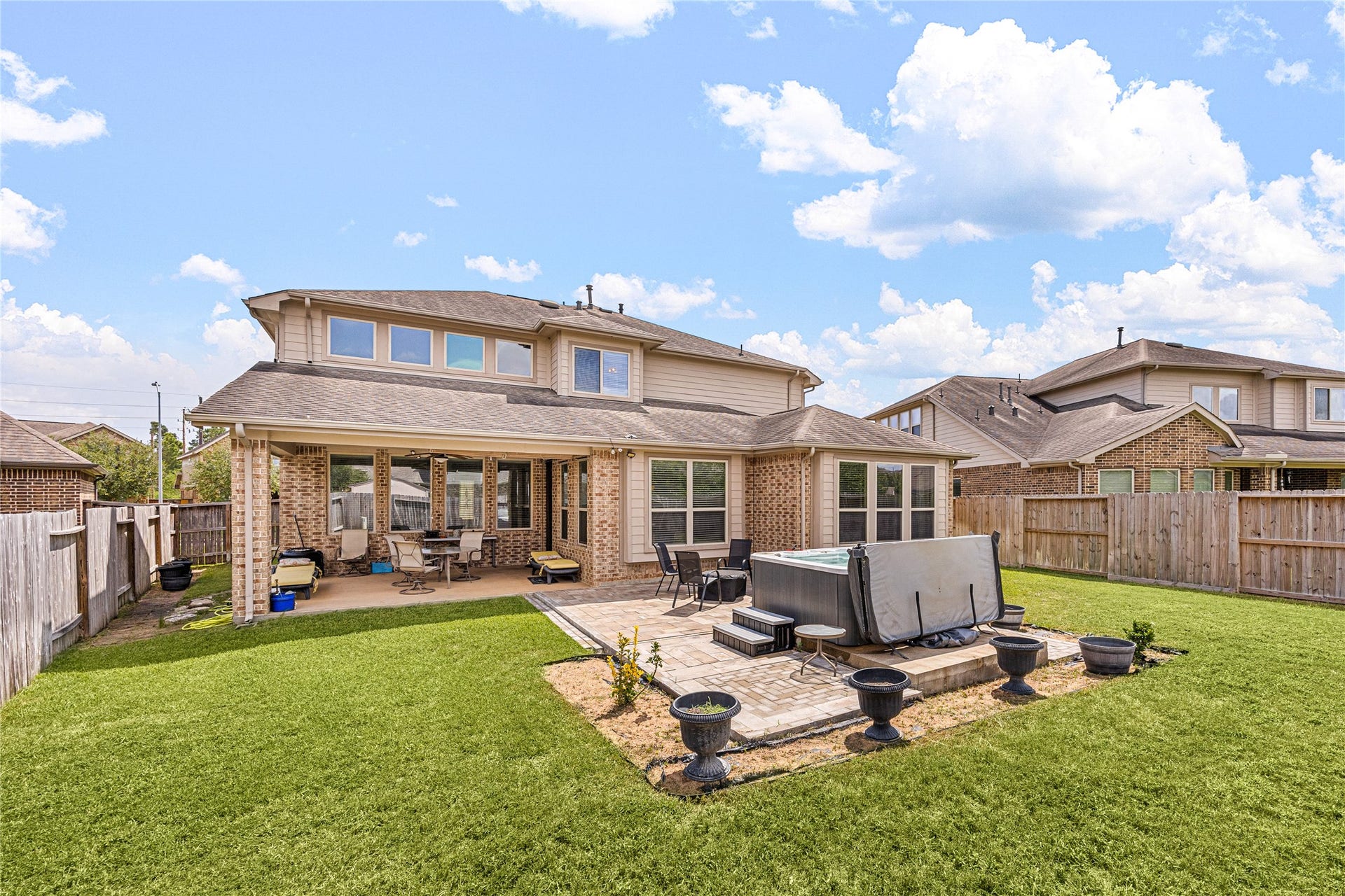 18707 Fox Kestrel Trail, Cypress, TX 77429 Spacious backyard featuring a covered patio and a luxurious hot tub, perfect for relaxation and entertaining.