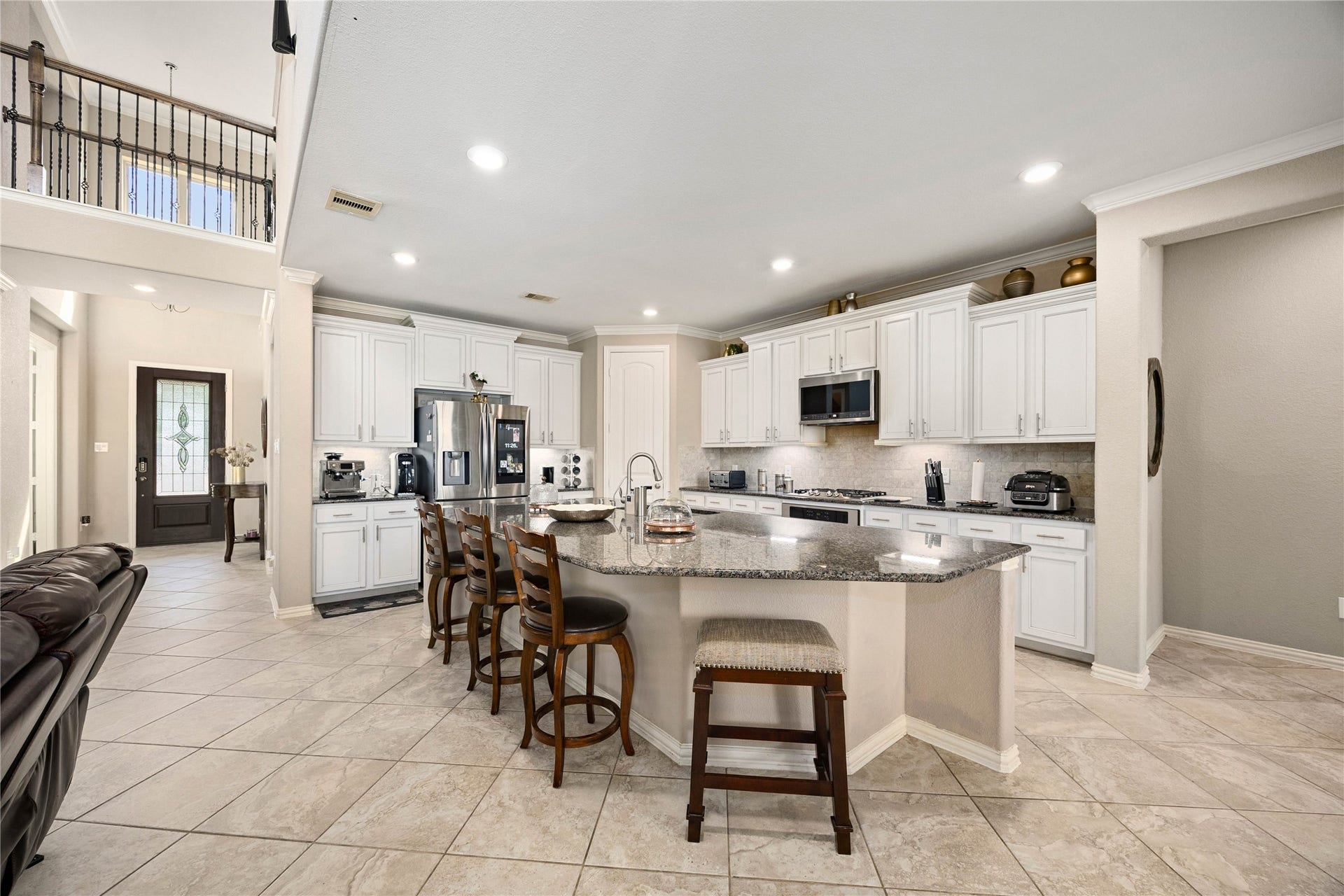 18707 Fox Kestrel Trail, Cypress, TX 77429 Spacious kitchen with modern stainless steel appliances, elegant granite countertops, and ample white cabinetry. An inviting island with seating is perfect for casual dining and entertaining.
