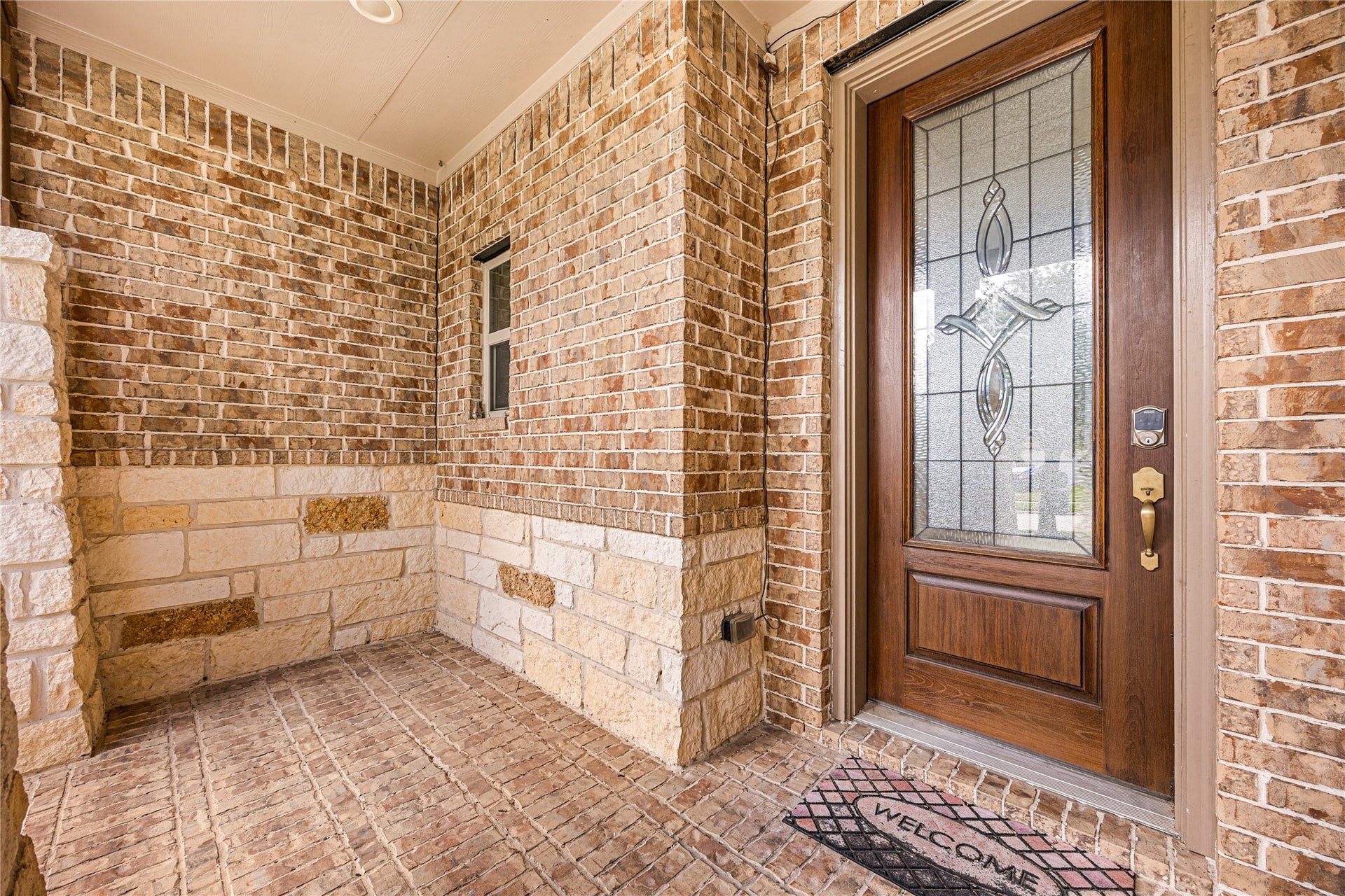 18707 Fox Kestrel Trail, Cypress, TX 77429 Charming entryway with elegant brickwork and a stylish wooden door featuring decorative glass, offering a warm welcome.