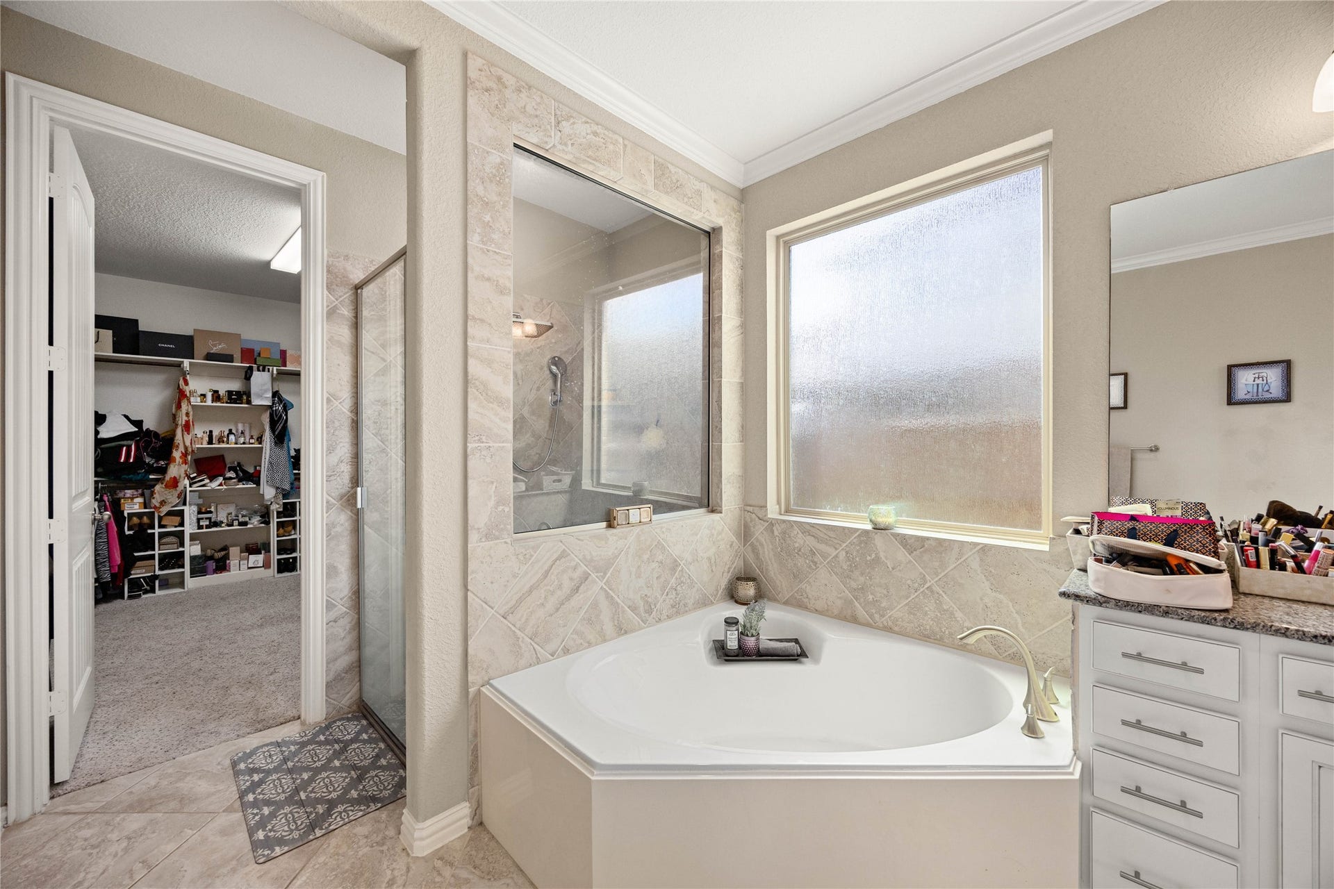 18707 Fox Kestrel Trail, Cypress, TX 77429 Luxurious bathroom featuring a spacious corner tub, sleek glass-enclosed shower, and ample natural light from frosted windows, seamlessly connected to a large walk-in closet.