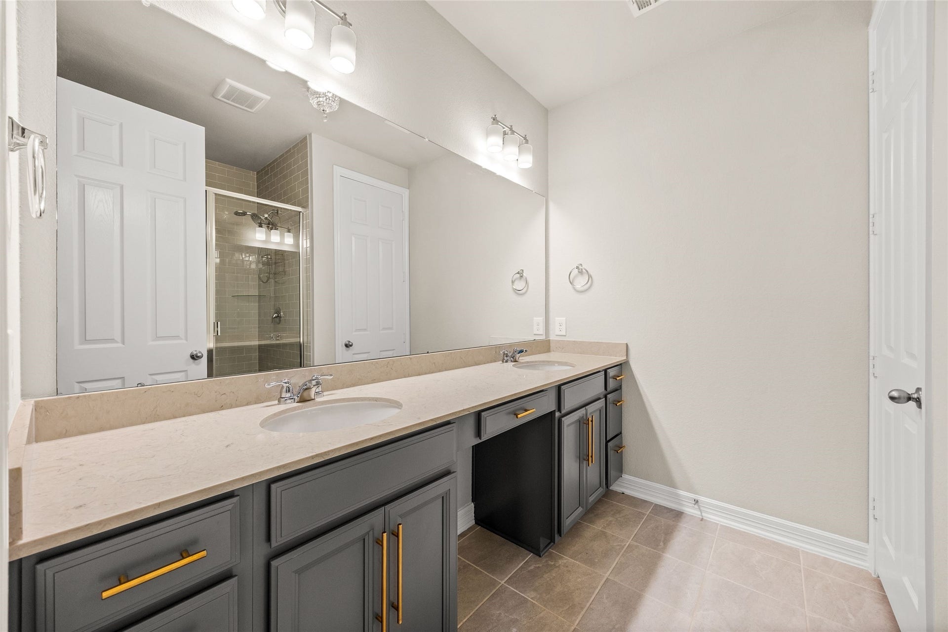 18223 Crystal Knoll Drive, Cypress, TX 77433 The primary bath gets a stylish update with gray cabinetry, gold hardware, dual sinks, and an extra-long vanity offering plenty of counter and storage space.