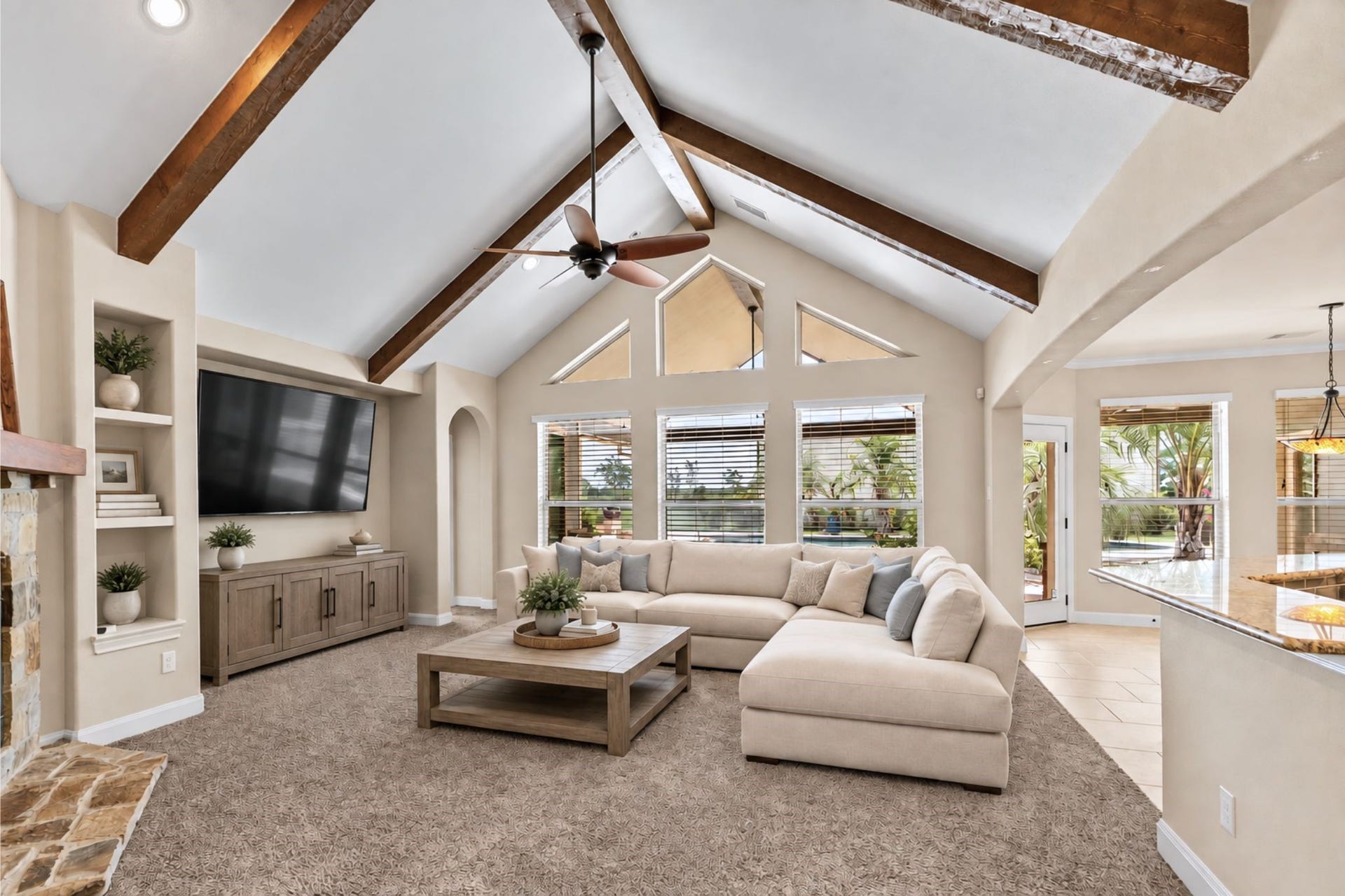 Spacious living room featuring vaulted ceilings with exposed beams, a cozy fireplace, and abundant natural light from large windows. **VIRTUAL STAGING, DECOR ONLY HAS BEEN ADDED**
