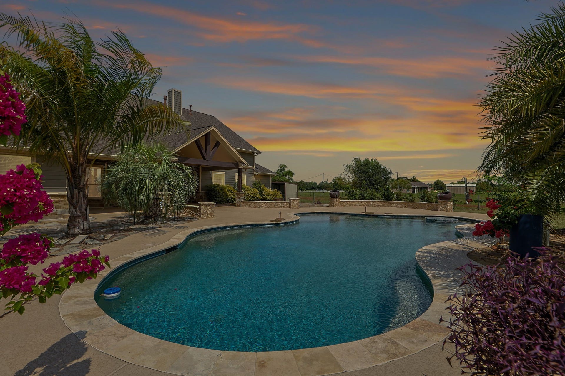 Experience luxury living with a stunning backyard oasis featuring a sparkling pool surrounded by lush landscaping and vibrant blooms, perfect for relaxation and entertaining.