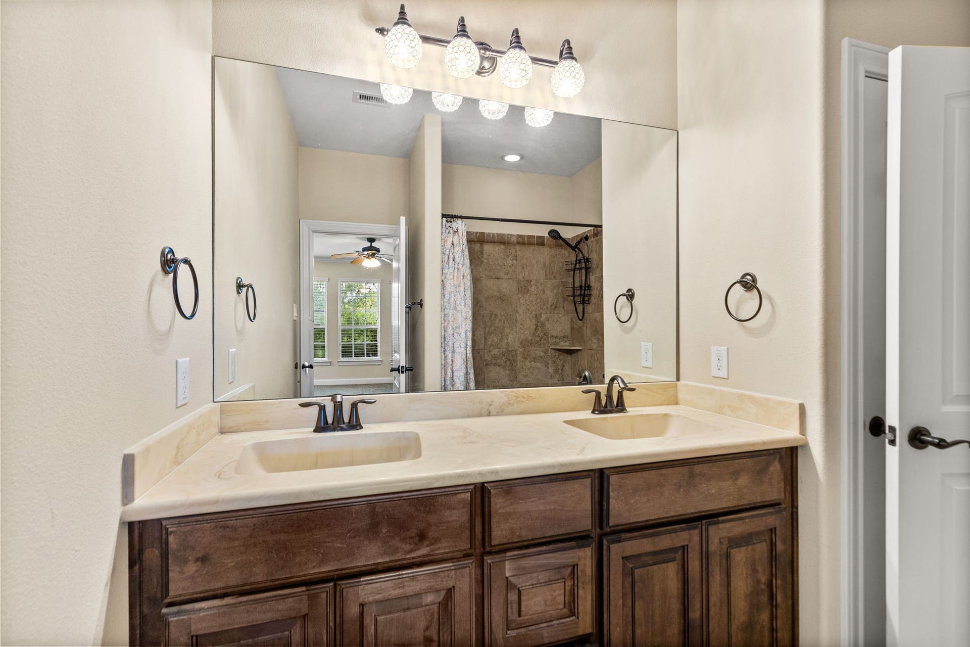 Elegant bathroom featuring a dual-sink vanity with rich wood cabinetry, complemented by a large mirror and stylish lighting.