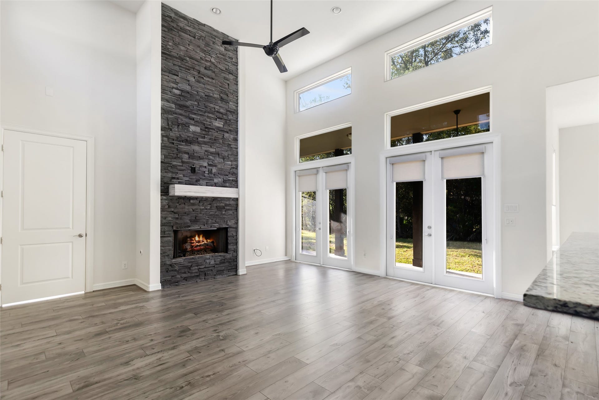 538 Magnolia Point Drive, Huffman, TX 77336 High ceilings with clerestory windows, transom-topped French doors, recessed lighting, stacked stone floor-to-ceiling propane-powered fireplace, natural light, and brand new flooring in the open living area