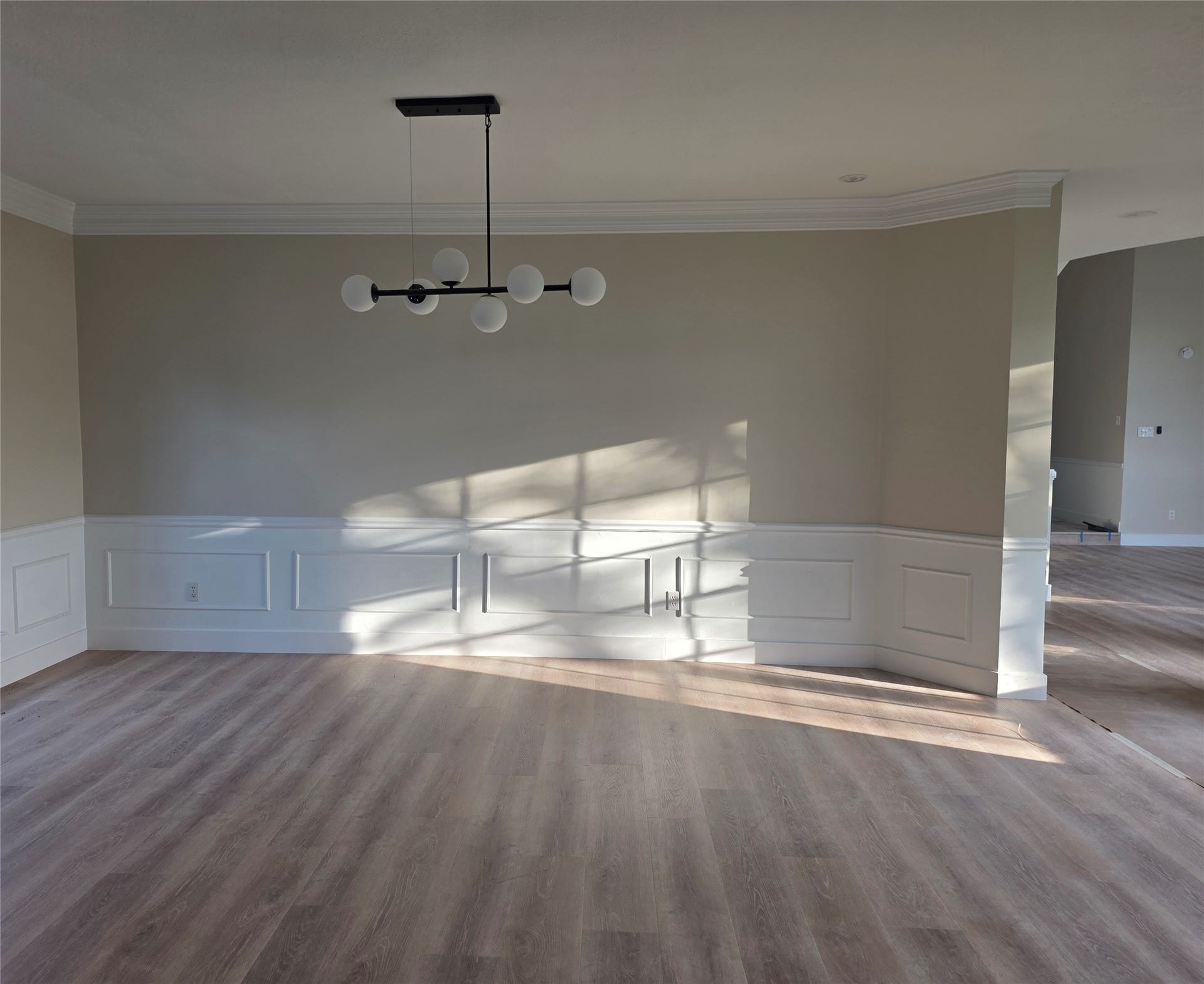 414 Mill Place CT, Sugar Land, TX 77498 Elegant and inviting dining room with wainscoting, crown molding, modern wood look flooring and stylish statement light fixture