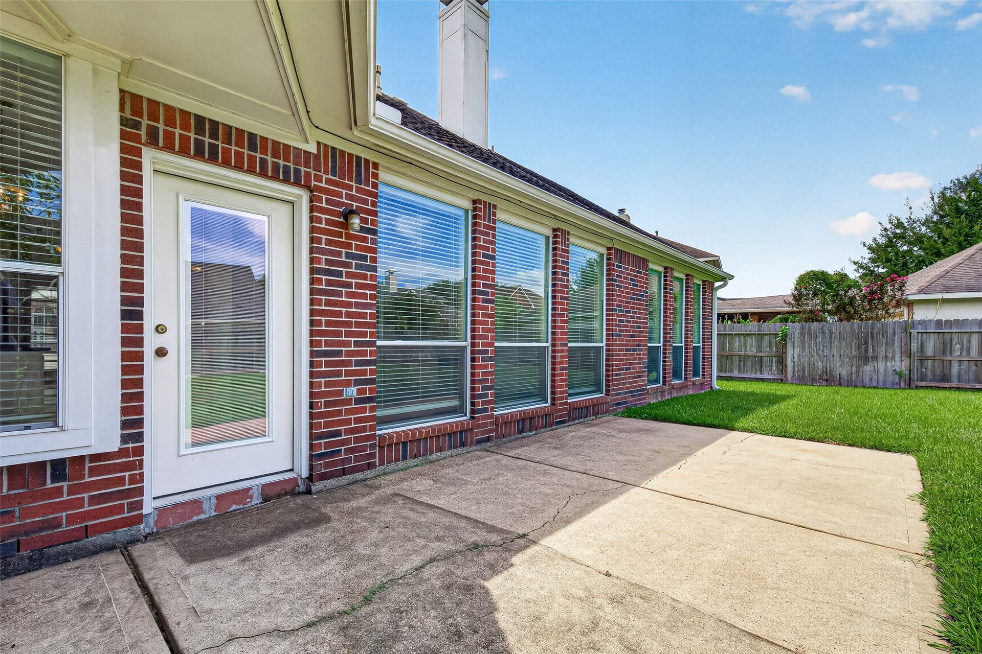 1711 Emma Cove Court, Sugar Land, TX 77479 Rear exterior features a brick faade, numerous windows, and convenient access to the patio.