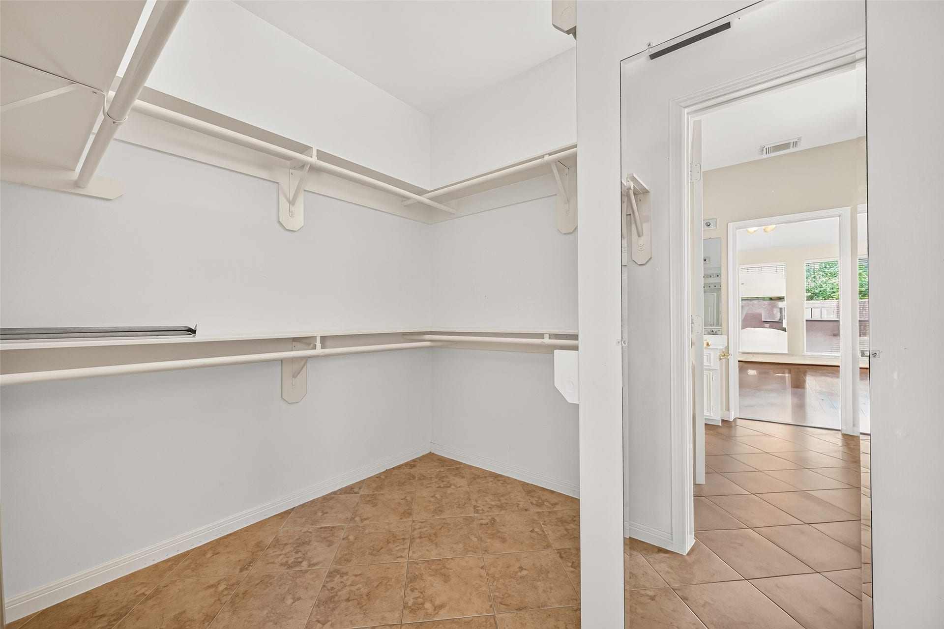 1711 Emma Cove Court, Sugar Land, TX 77479 Oversized primary closet provides extensive hanging space, built-in shelving, and easy-care tile flooring.