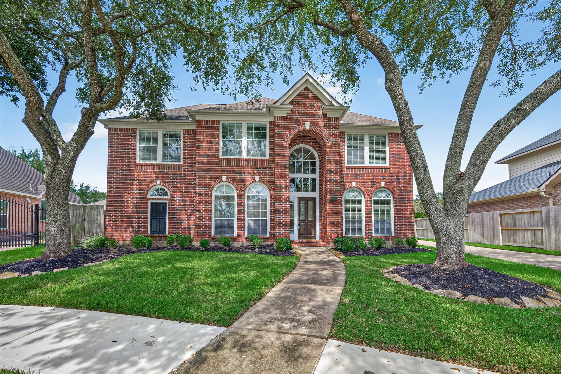 1711 Emma Cove Court, Sugar Land, TX 77479 Impressive curb appeal featuring a stately brick faade, arched windows, and a neatly maintained front lawn.