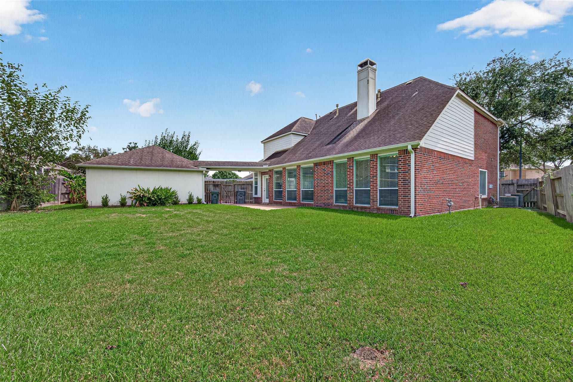1711 Emma Cove Court, Sugar Land, TX 77479 Full rear view highlights the homes brick construction, detached garage, and generous backyard.