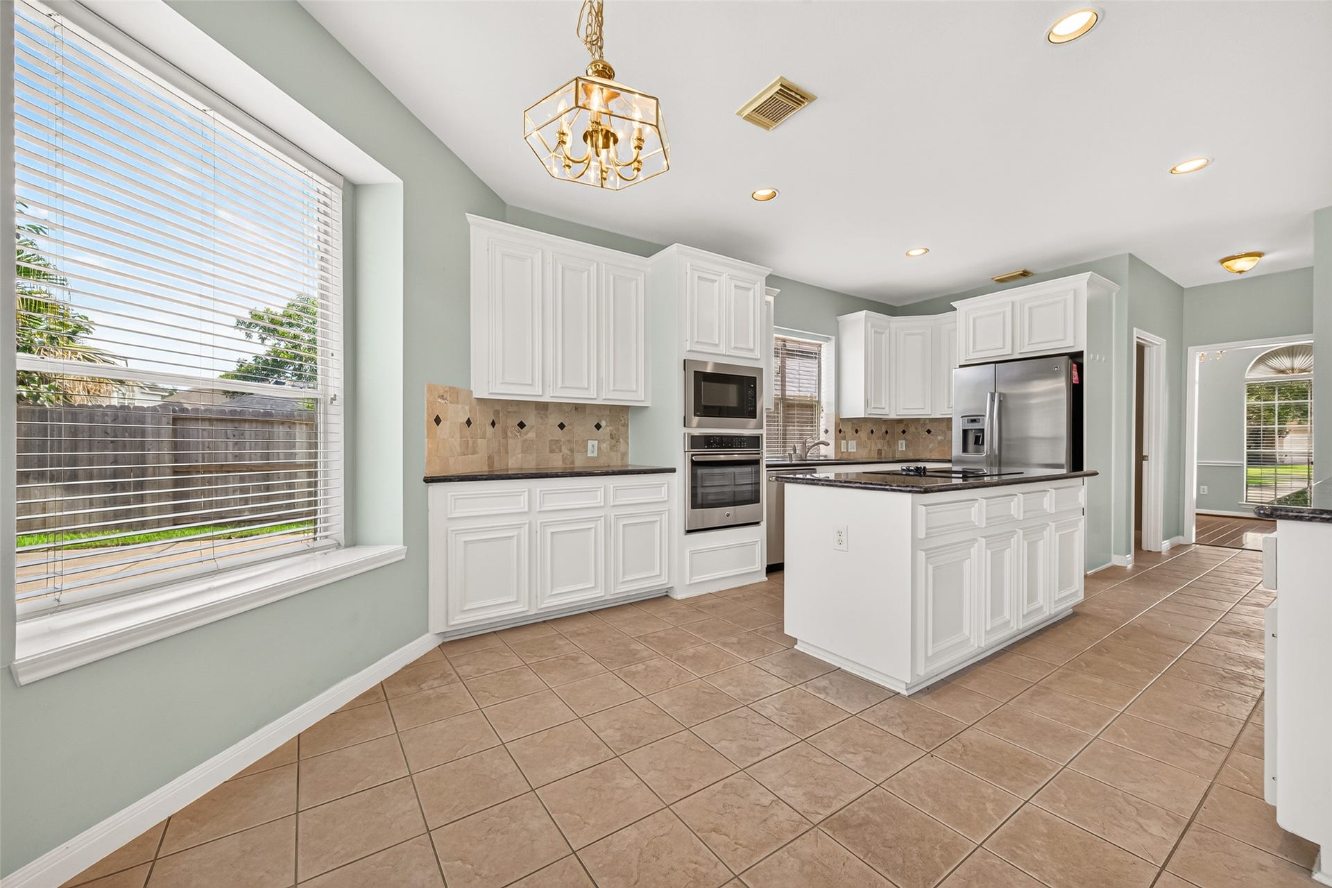 1711 Emma Cove Court, Sugar Land, TX 77479 Spacious kitchen features white cabinetry, dark countertops, a center island, stainless steel appliances, and a sunlit breakfast area.