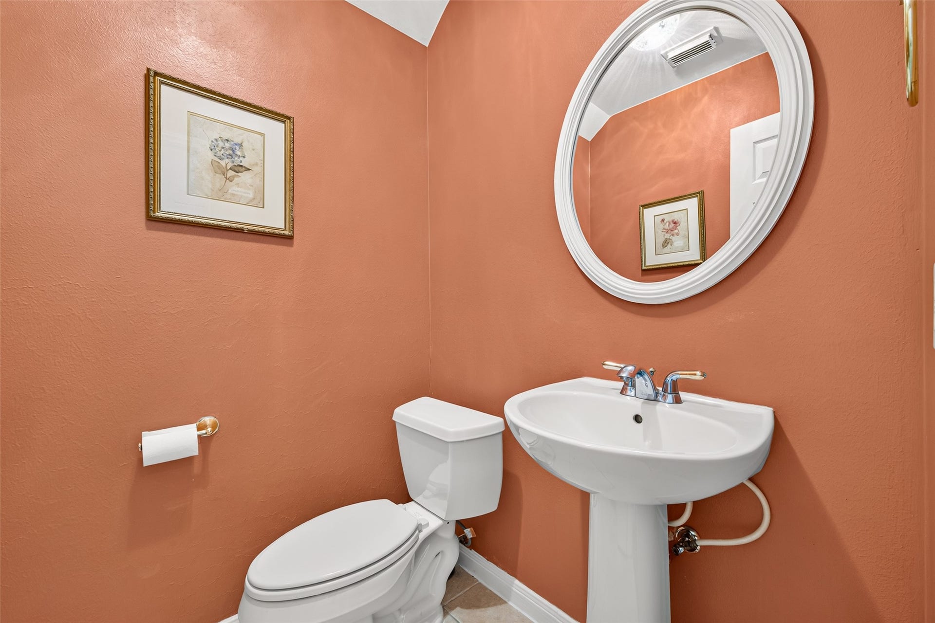 1711 Emma Cove Court, Sugar Land, TX 77479 Main-level powder room features a pedestal sink, oval mirror, and warm accent walls.