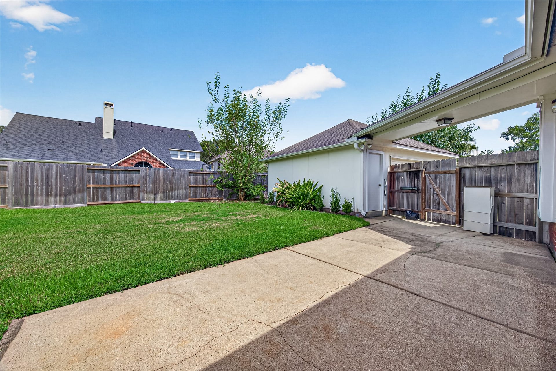 1711 Emma Cove Court, Sugar Land, TX 77479 Private outdoor space includes mature landscaping, a gated side entrance, and access to the garage.