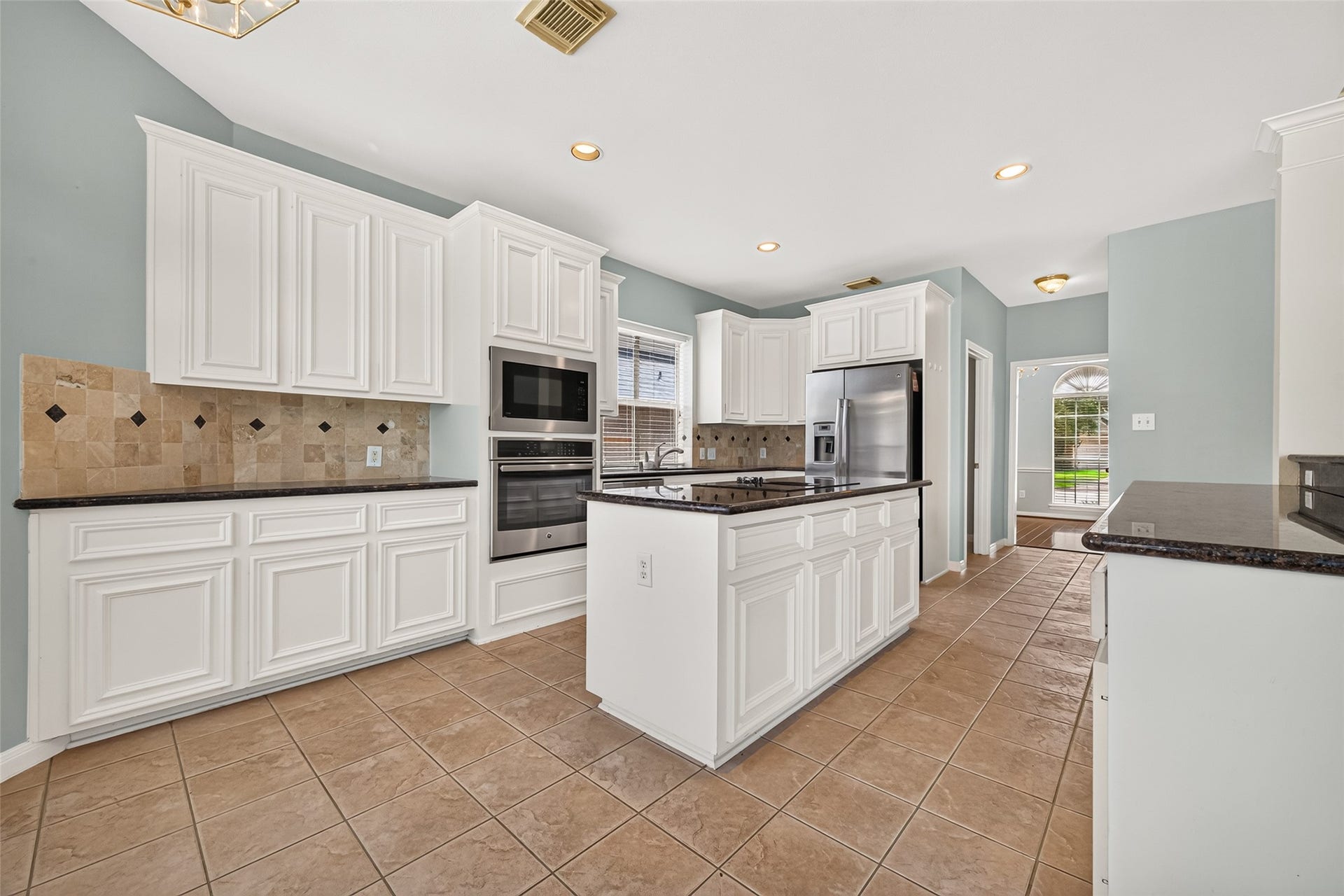 1711 Emma Cove Court, Sugar Land, TX 77479 Crisp white cabinets contrast beautifully with dark countertops and a decorative tile backsplash.